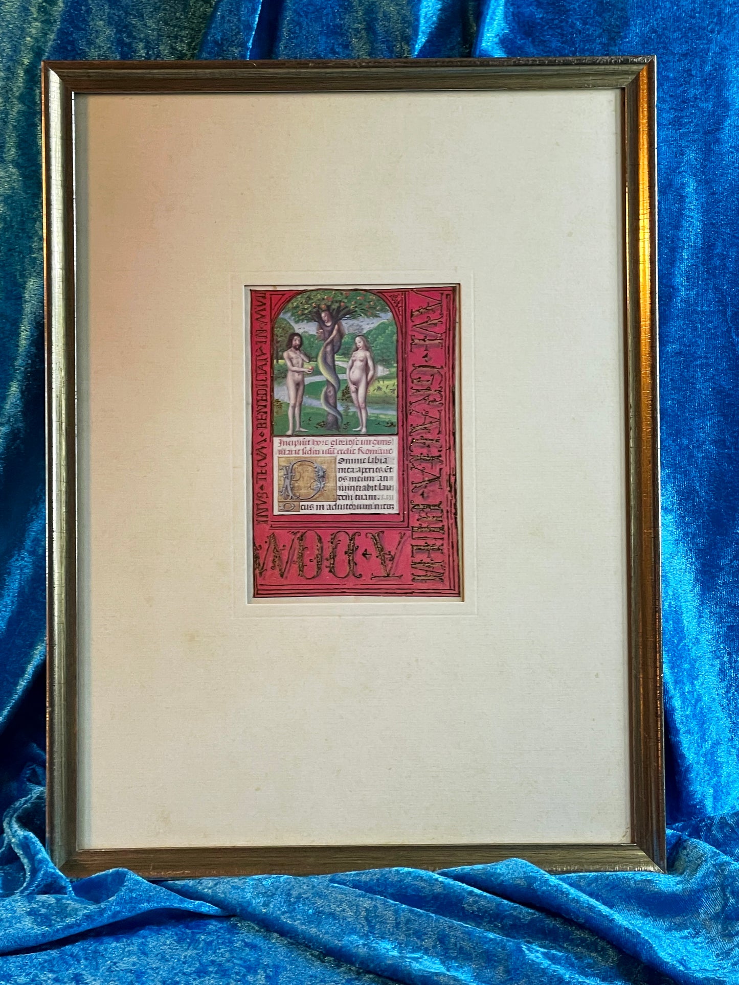 Adam and Eve illuminated miniature in silvered frame shown at an angle on blue velvet