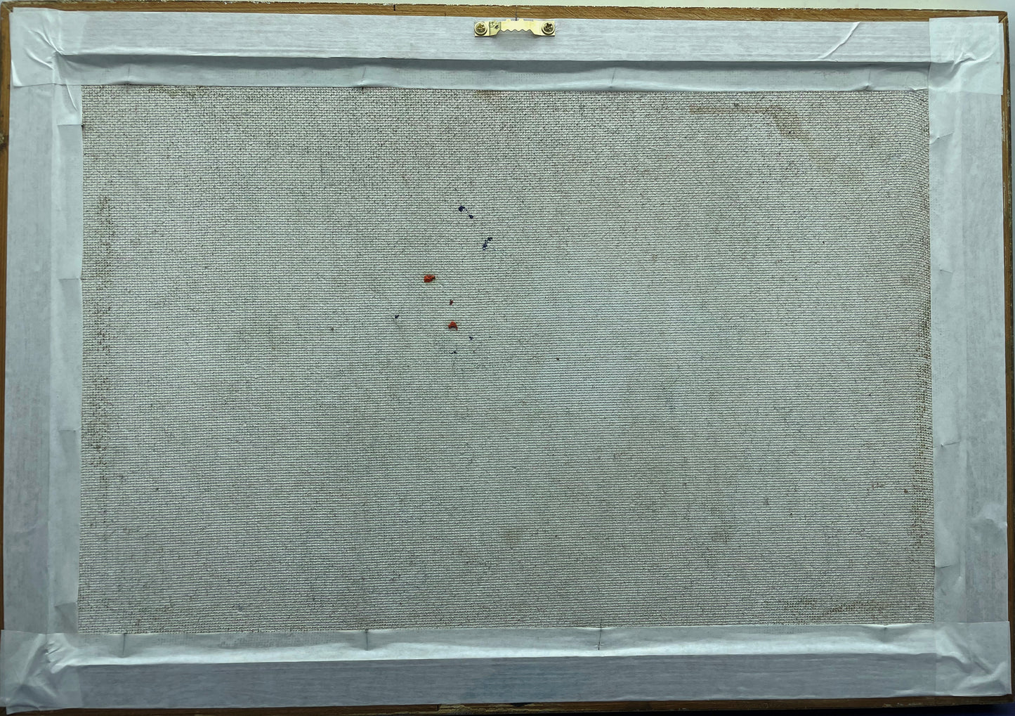 Reverse of the framed painting showing the canvas-backed board and hanging fitting