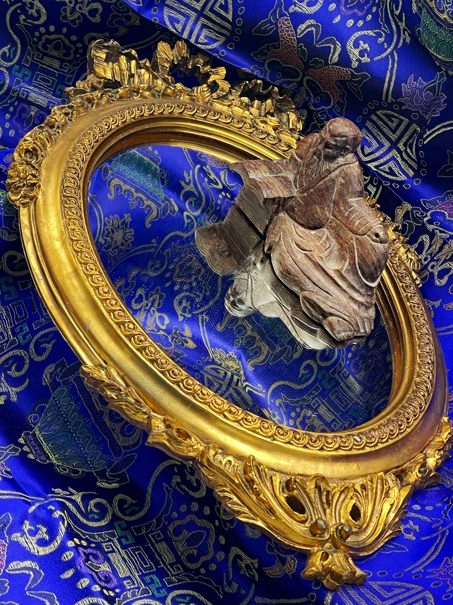Richly ornamented gilt oval mirror with carved scrollwork frame