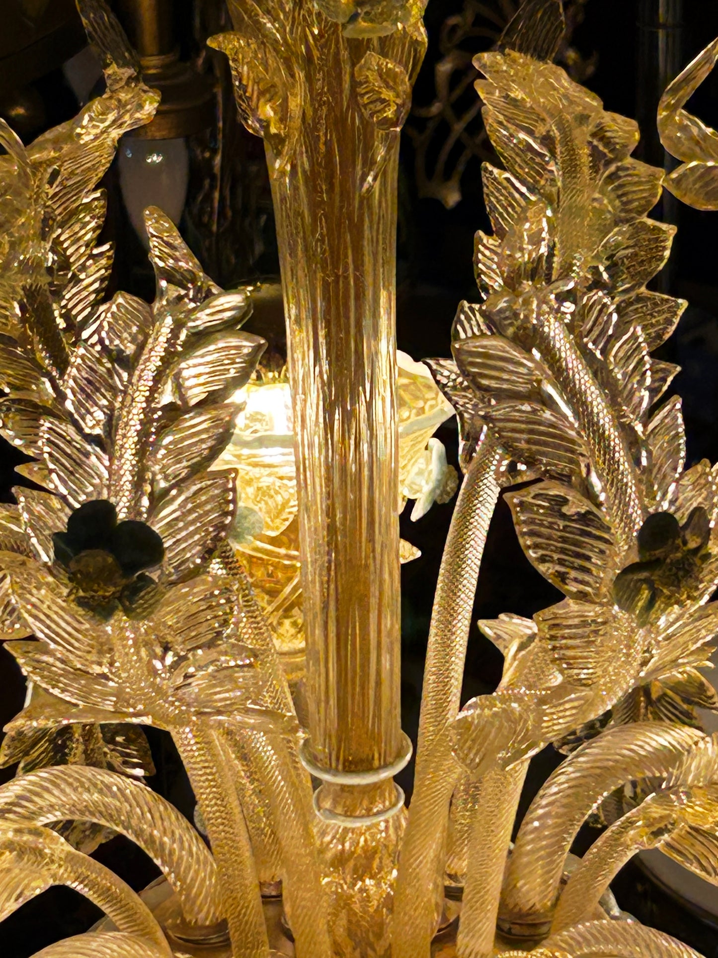 Murano glass chandelier shown lit, golden glow across the Venetian glass