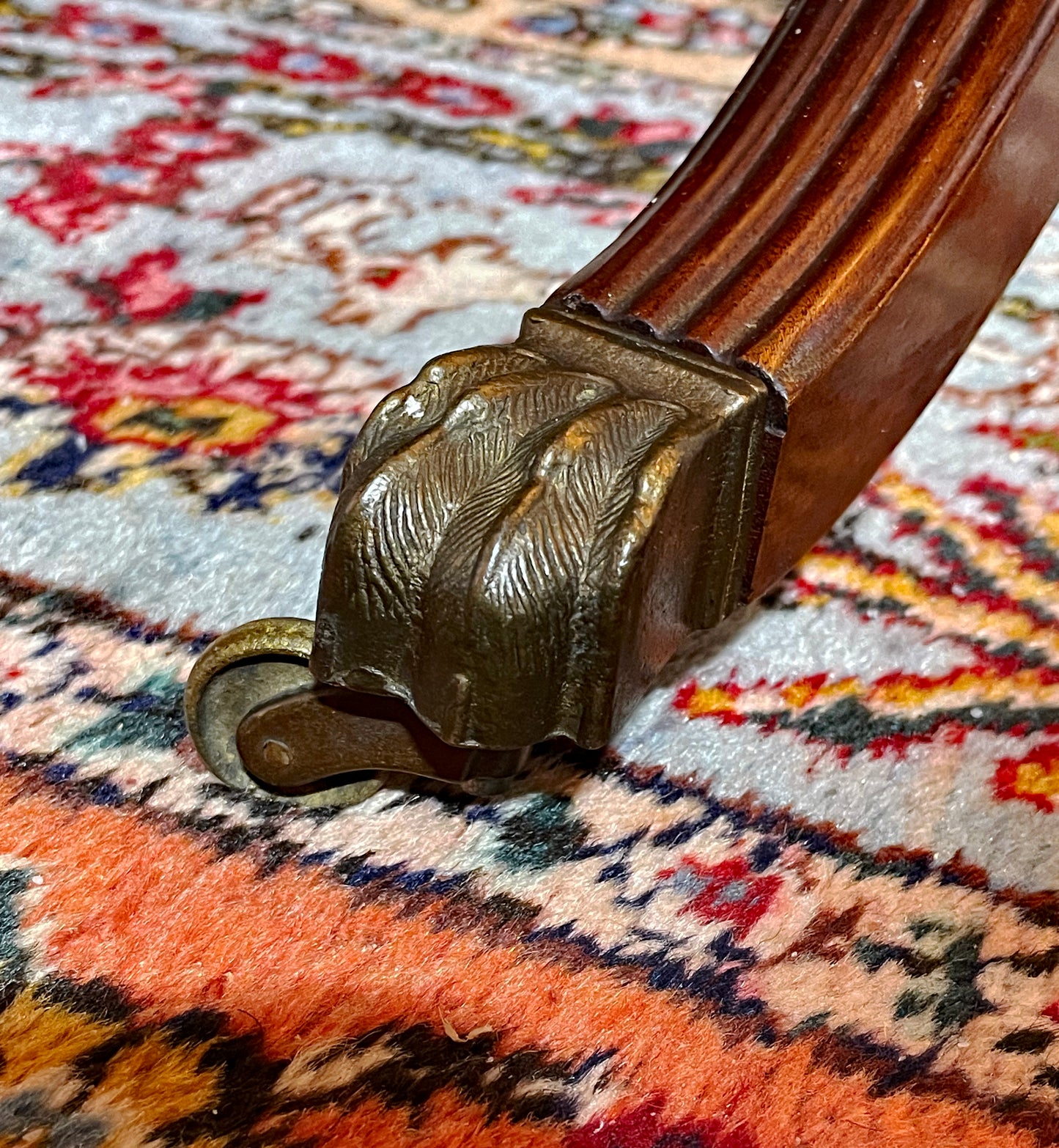 Original cast brass lion-paw castor on the reeded splayed leg of the mahogany table