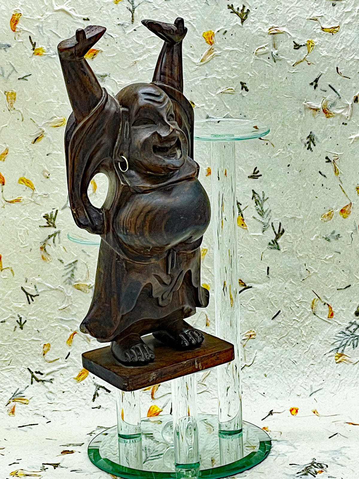Vintage solid ebony Happy Buddha statue with raised arms, front view on wooden plinth