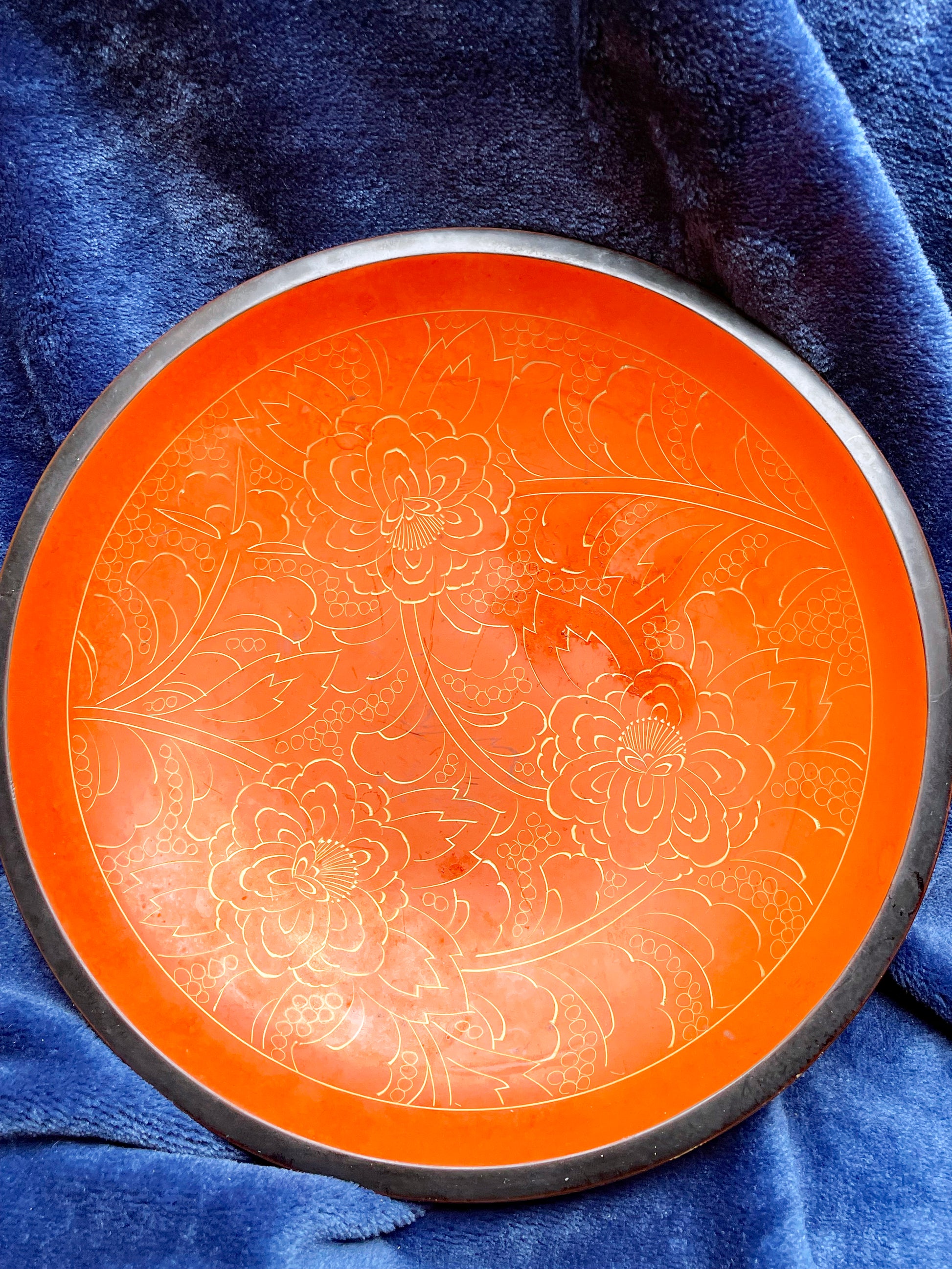 Top-down view of Chinese qiangjin lacquer plate with gold-engraved peonies on a coral-orange ground