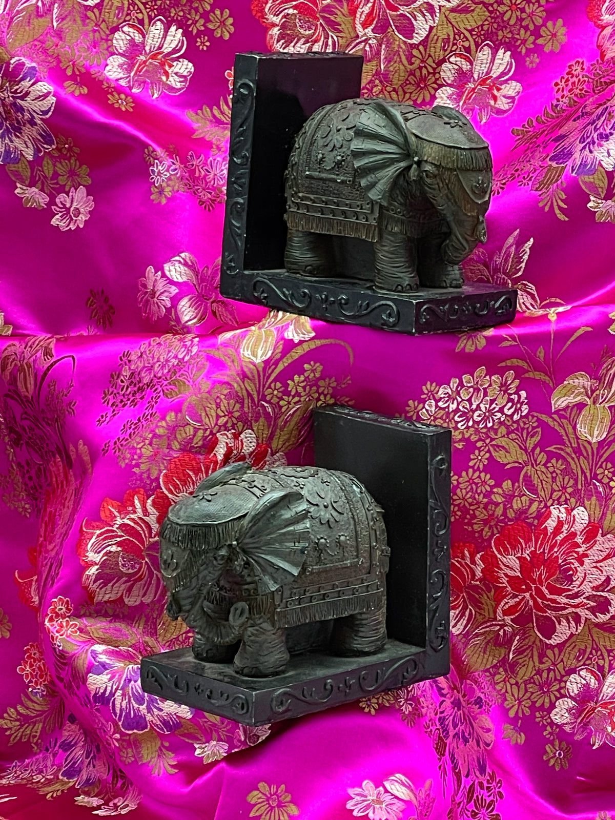 Pair of antique bronze patinated cast stone elephant bookends on pink brocade silk