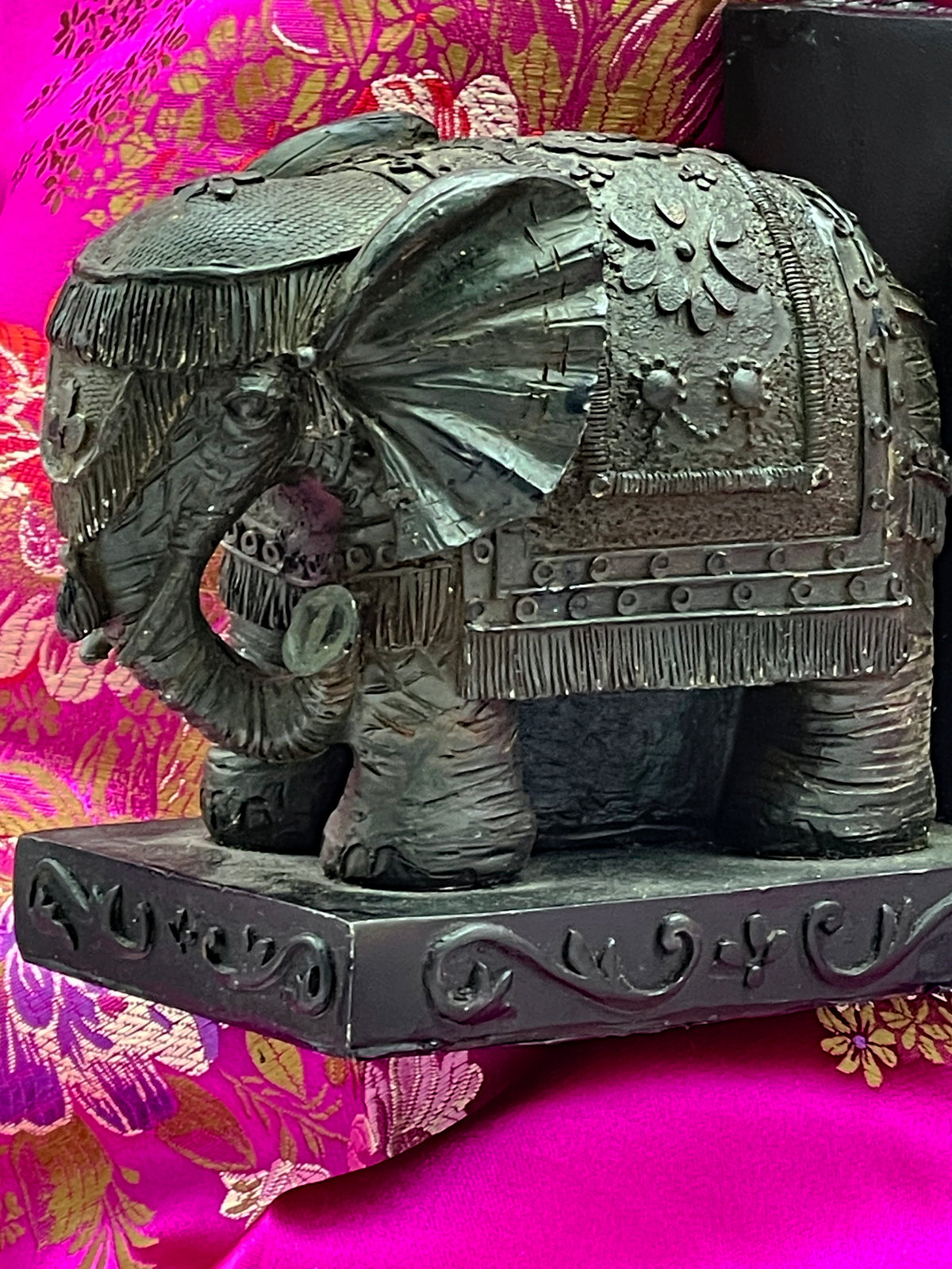 Full side view of one elephant bookend on its relief decorated plinth