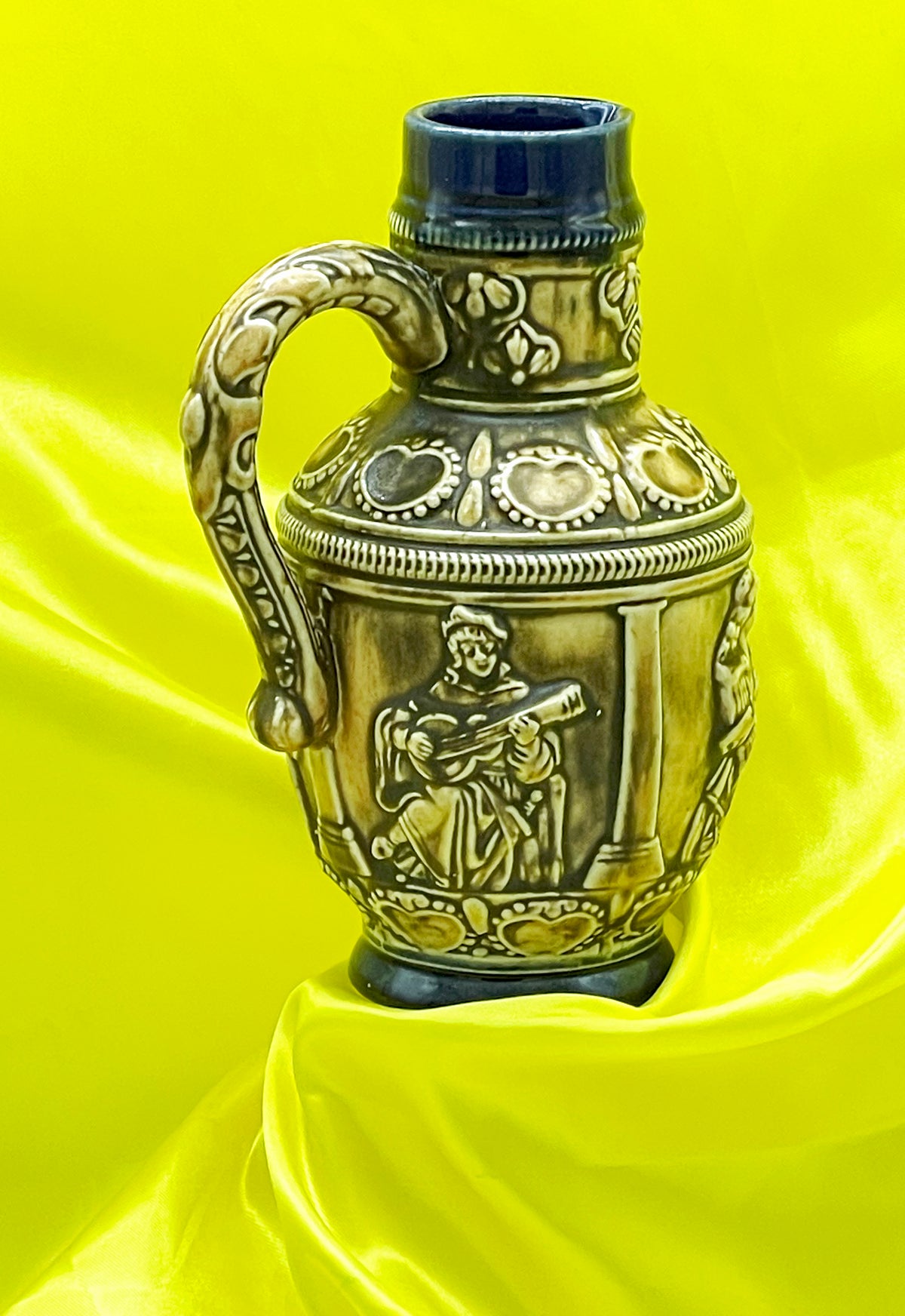 Full view of vintage German Henkelkrug showing lute player relief between columns