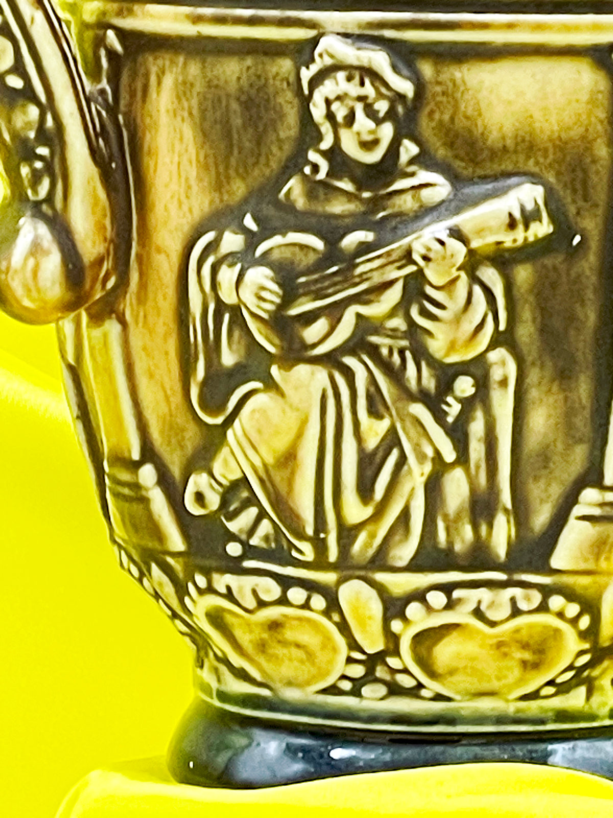 Close up of lute playing musician relief on vintage West German ceramic jug