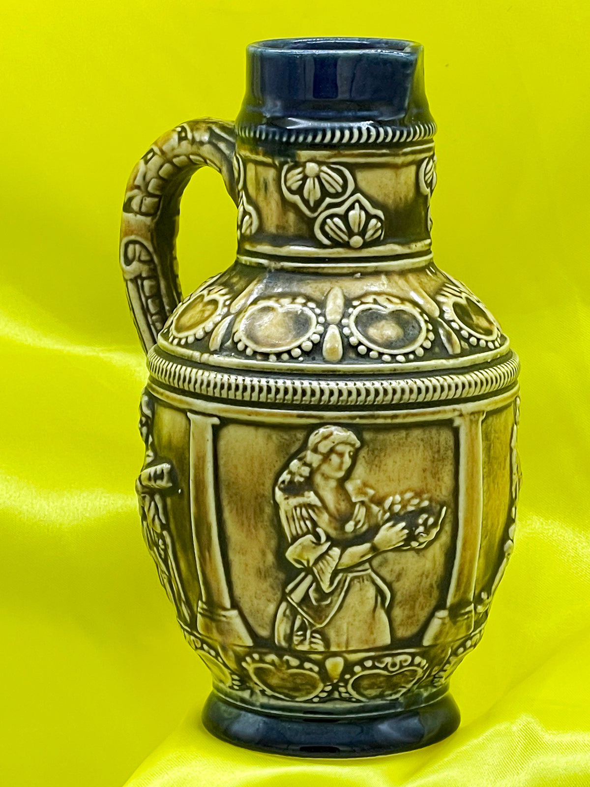 Side view of vintage German relief jug showing dancer figure with garland