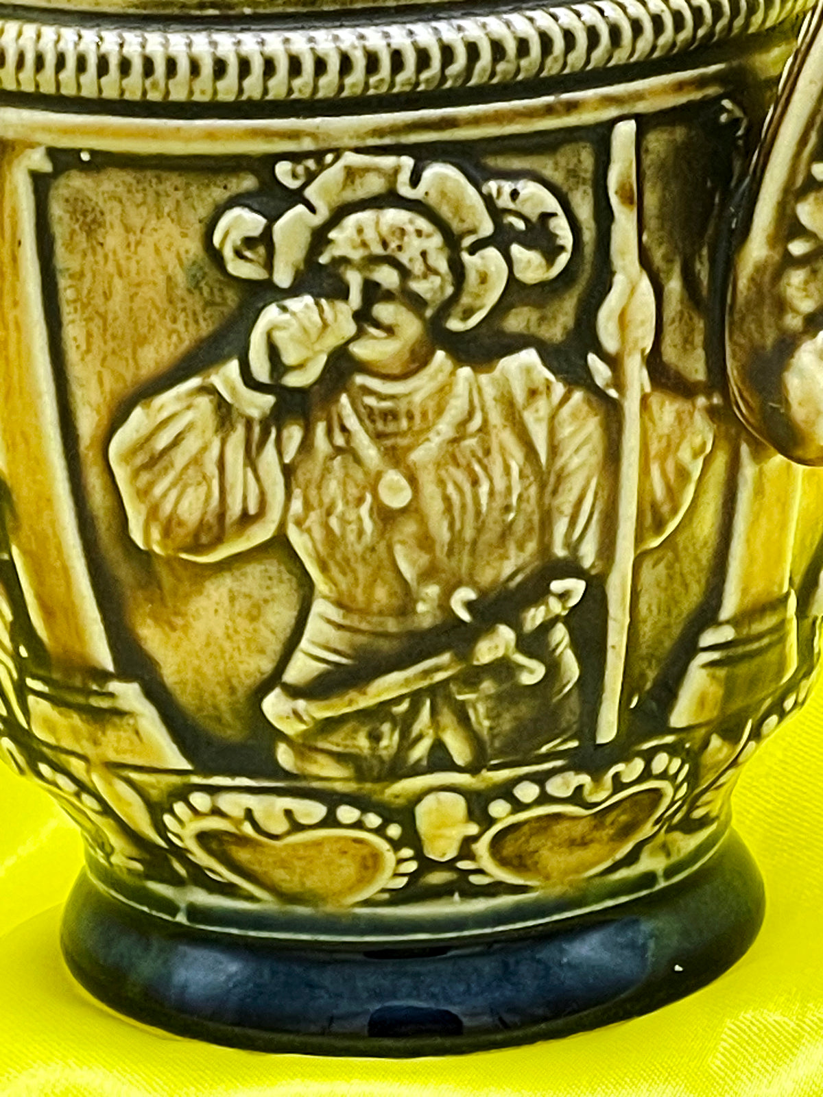 Close up of drinking reveller relief on vintage West German ceramic jug