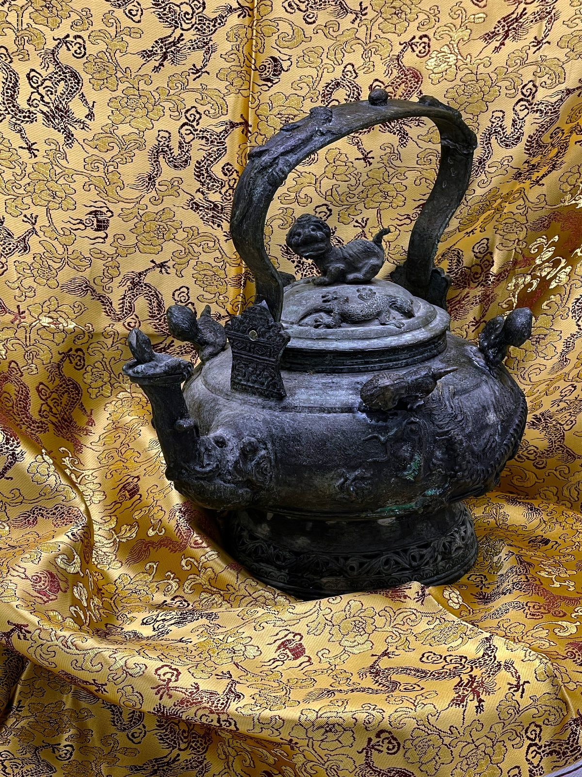 Full view of heavy Chinese bronze teapot with foo lion finial, arched branch handle and elephant head spout