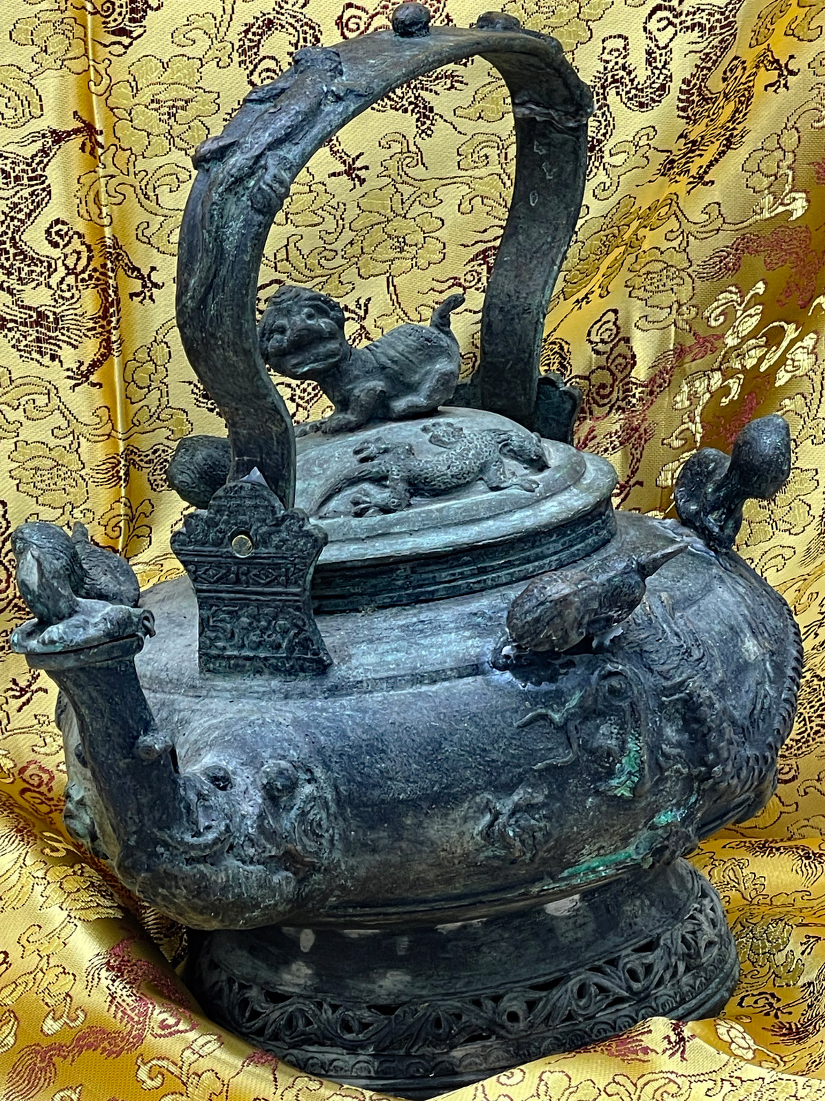 Side view of antique Chinese bronze ritual vessel showing bird appliques and pierced foliate foot