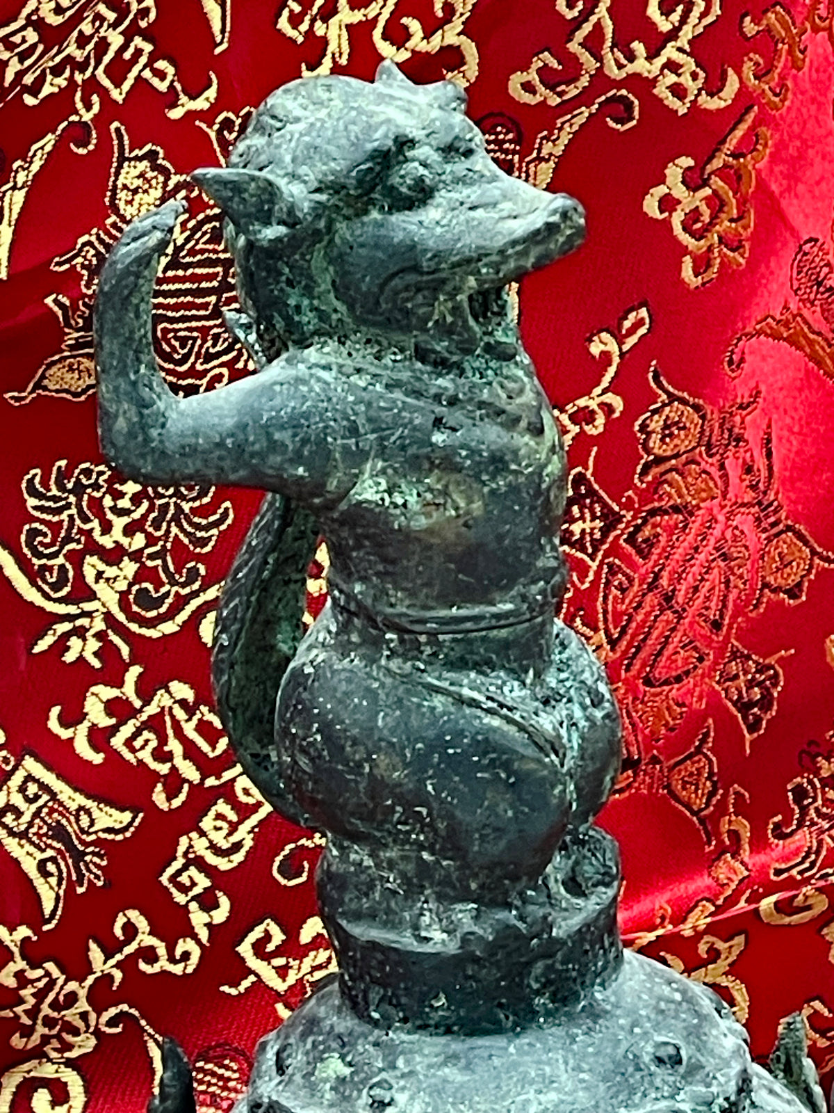 Close up of the mythical guardian figure with raised arm on the antique Chinese bronze bell