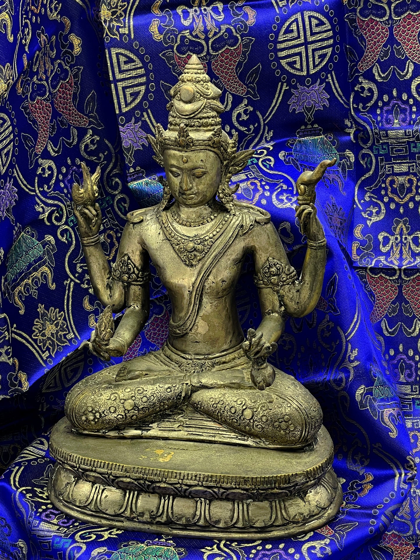 Seated four armed bronze Vishnu statue with serene face and jewelled crown, front angle