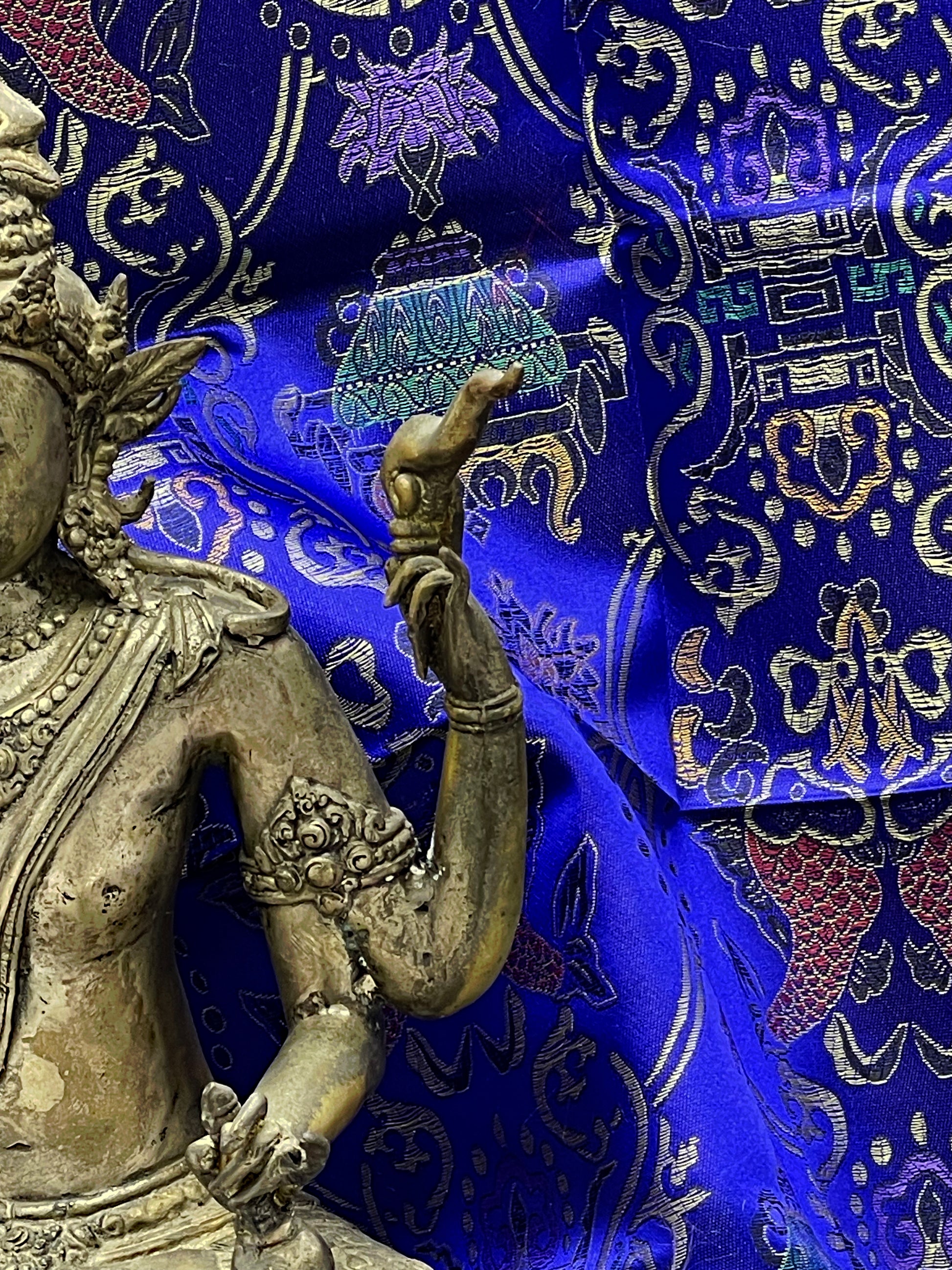 Detail of Vishnu hand holding sacred attribute against blue brocade backdrop
