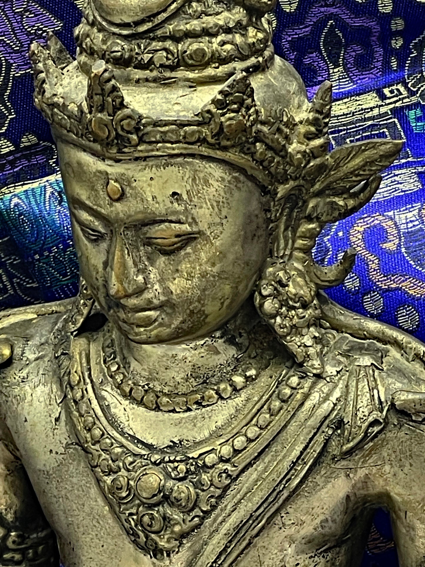 Close up of Vishnu bronze face and elaborate crown with beaded necklaces and gilding traces