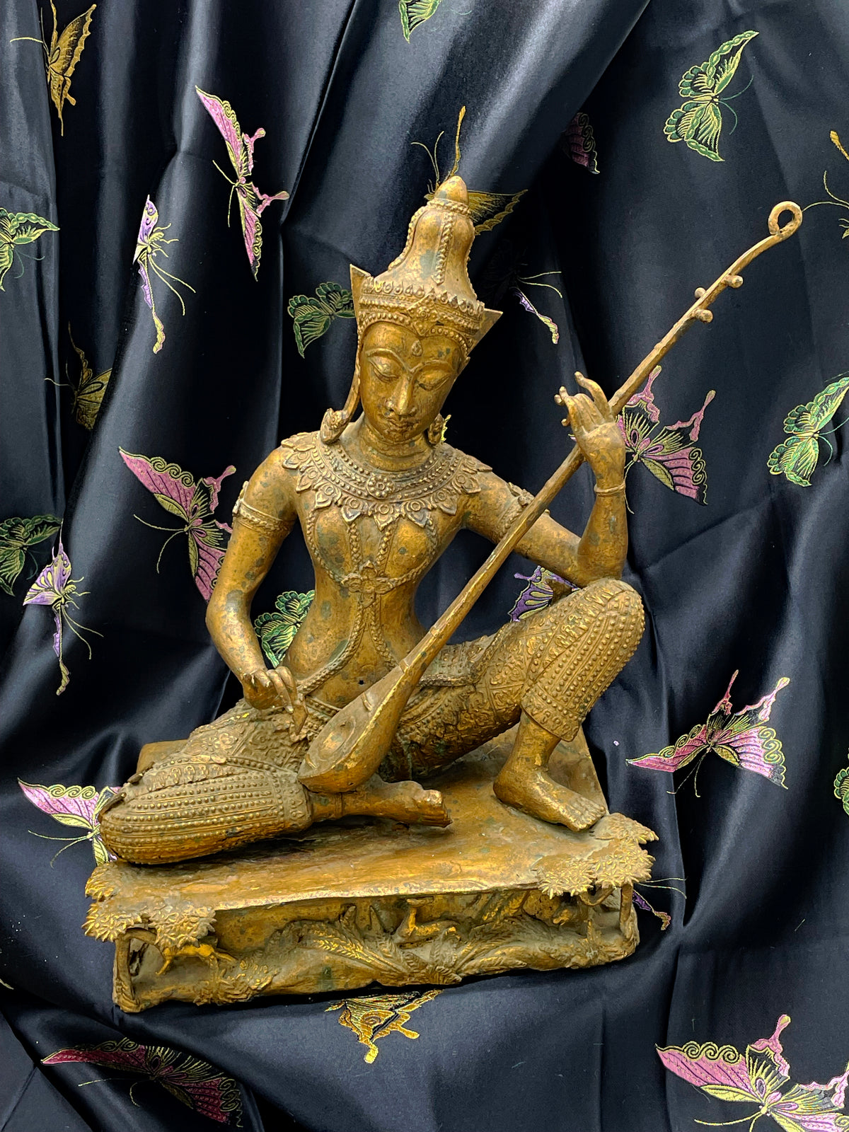 Full front view of antique Thailand gilded bronze Saraswati musician statue with towering crown