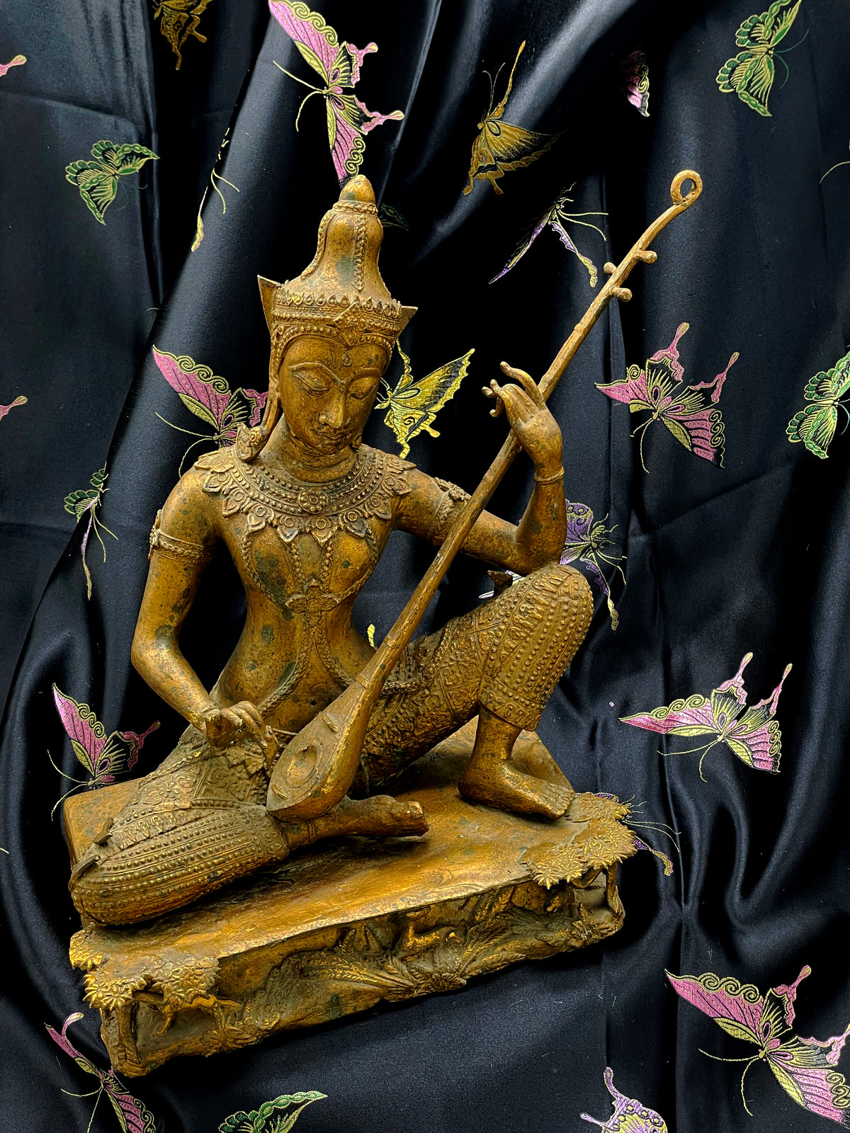Antique gilded bronze Saraswati statue from Thailand seated on sculpted base, three quarter view