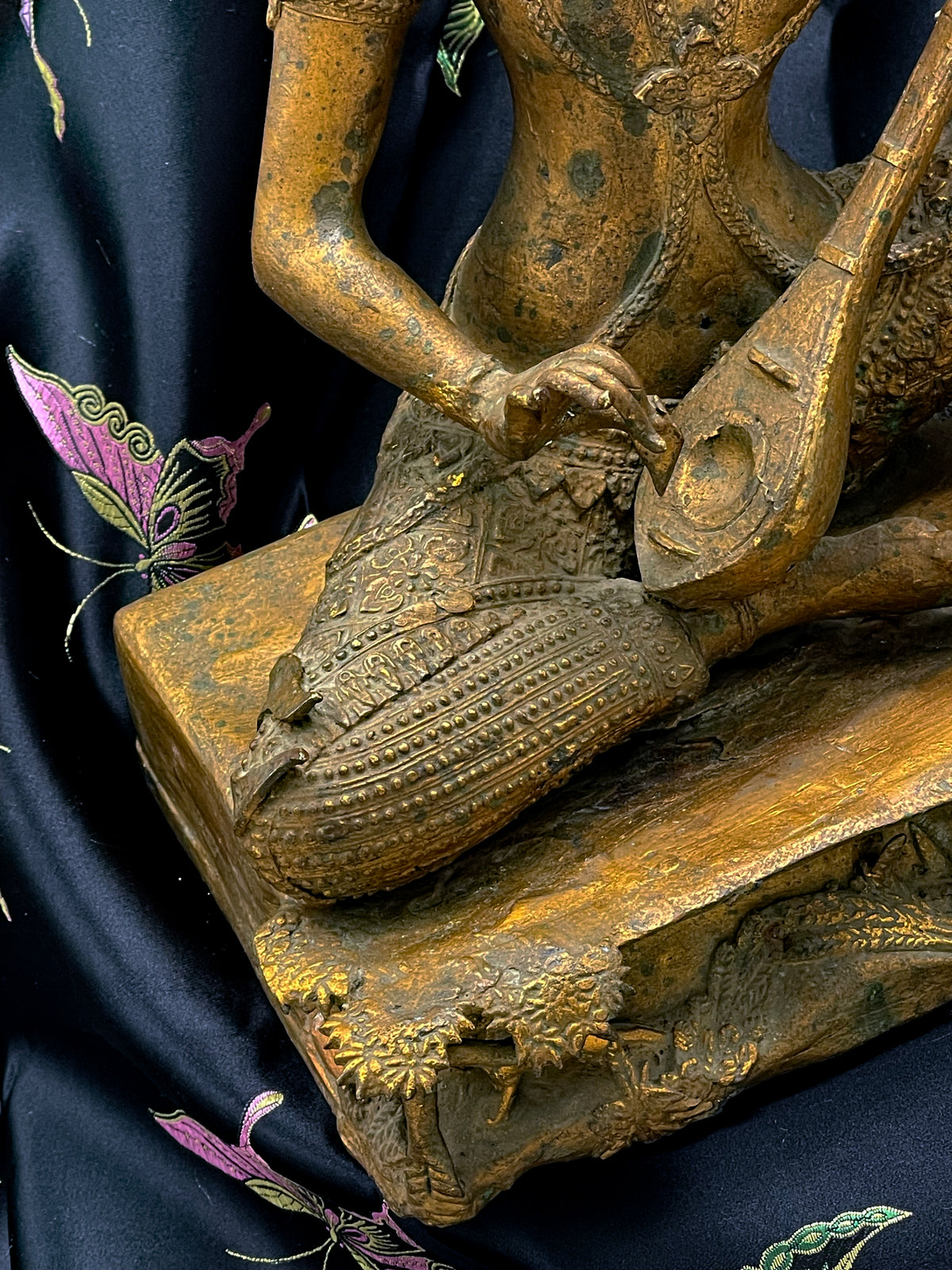 Detail of the vina, beaded court dress and sculpted base of the Thai gilded bronze statue