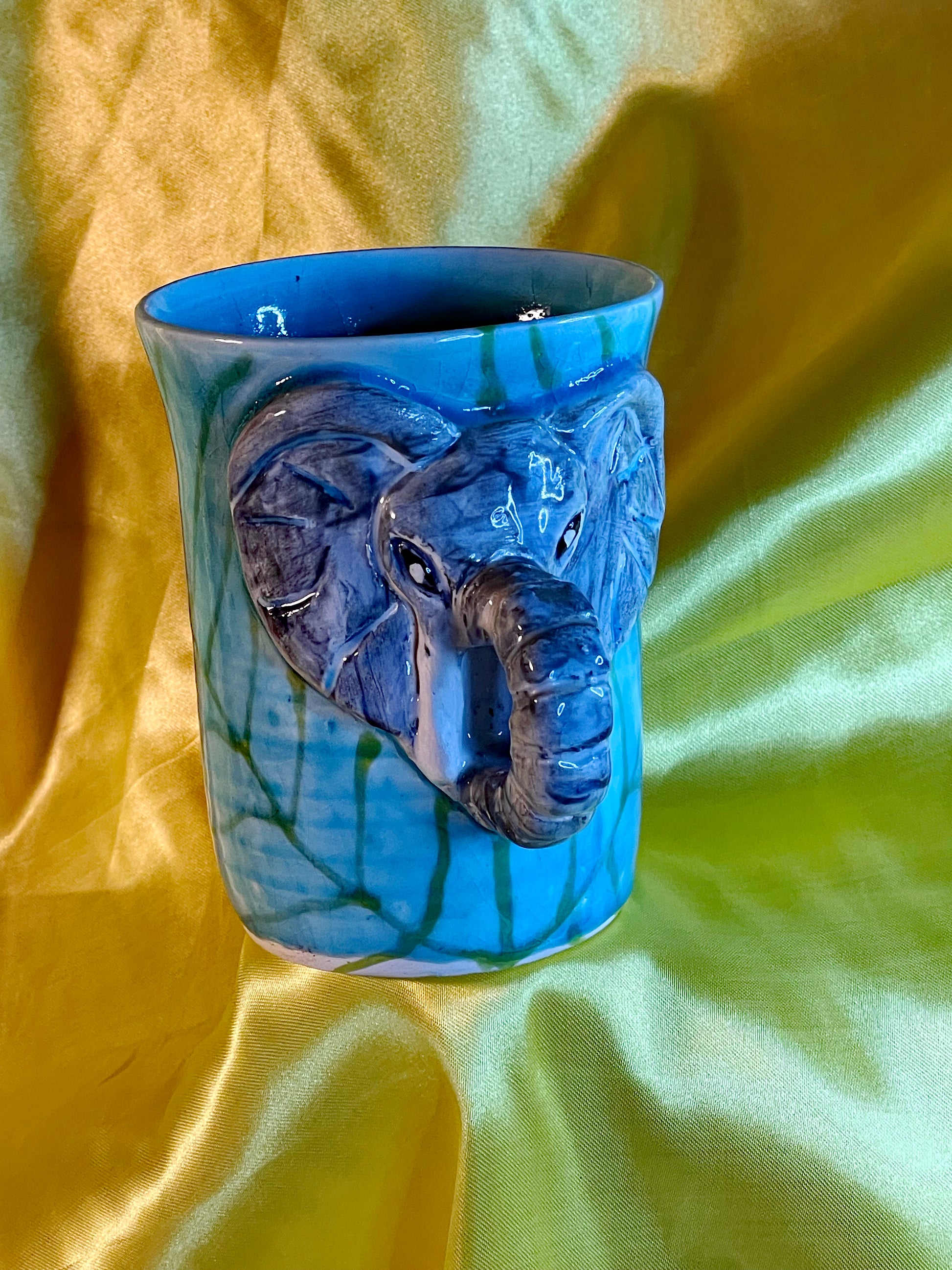 Turquoise Thai celadon mug with a sculpted grey elephant head and trunk handle in high relief