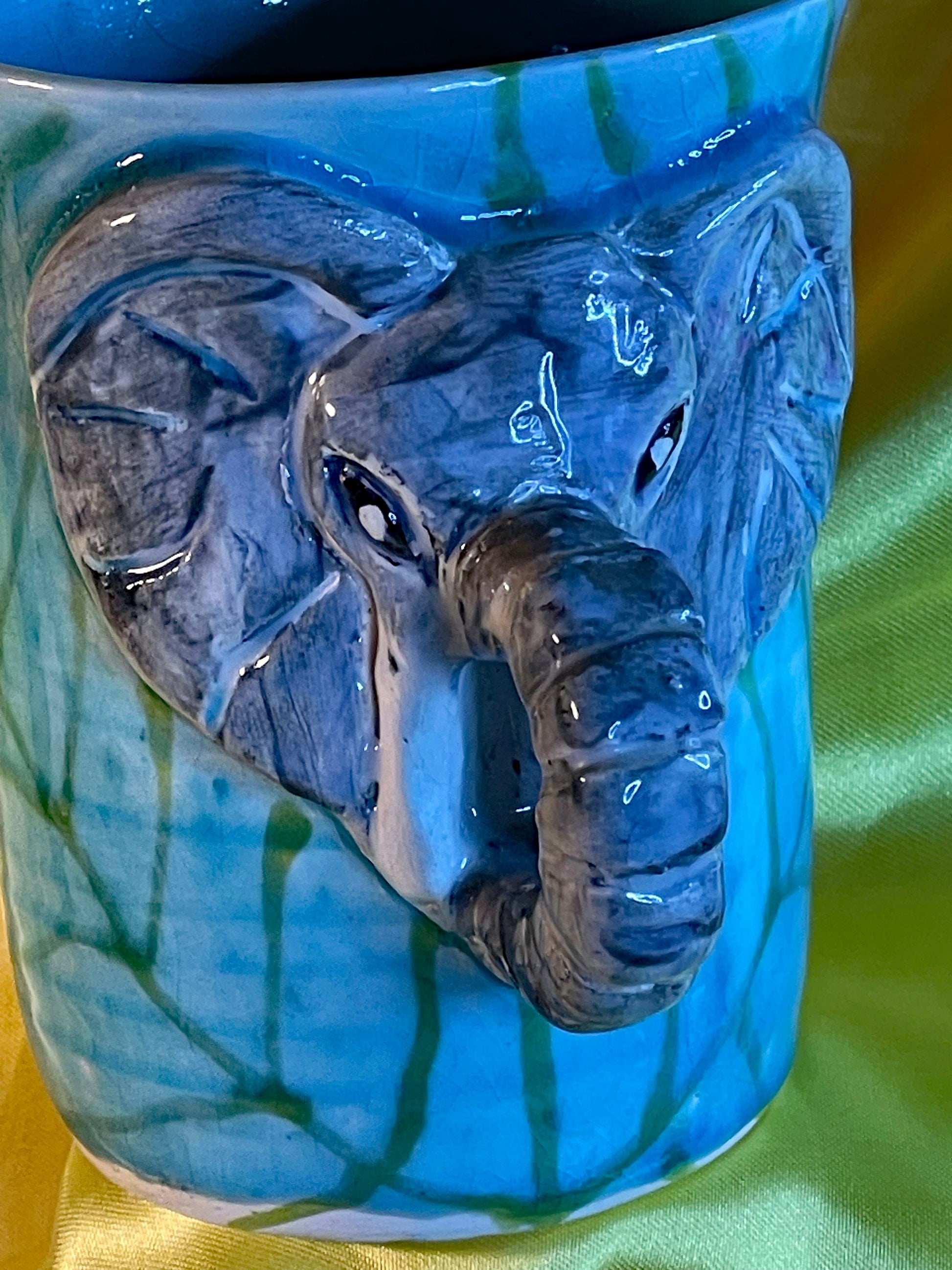 Close-up of the hand-modelled elephant face and curled trunk handle on the turquoise glazed mug