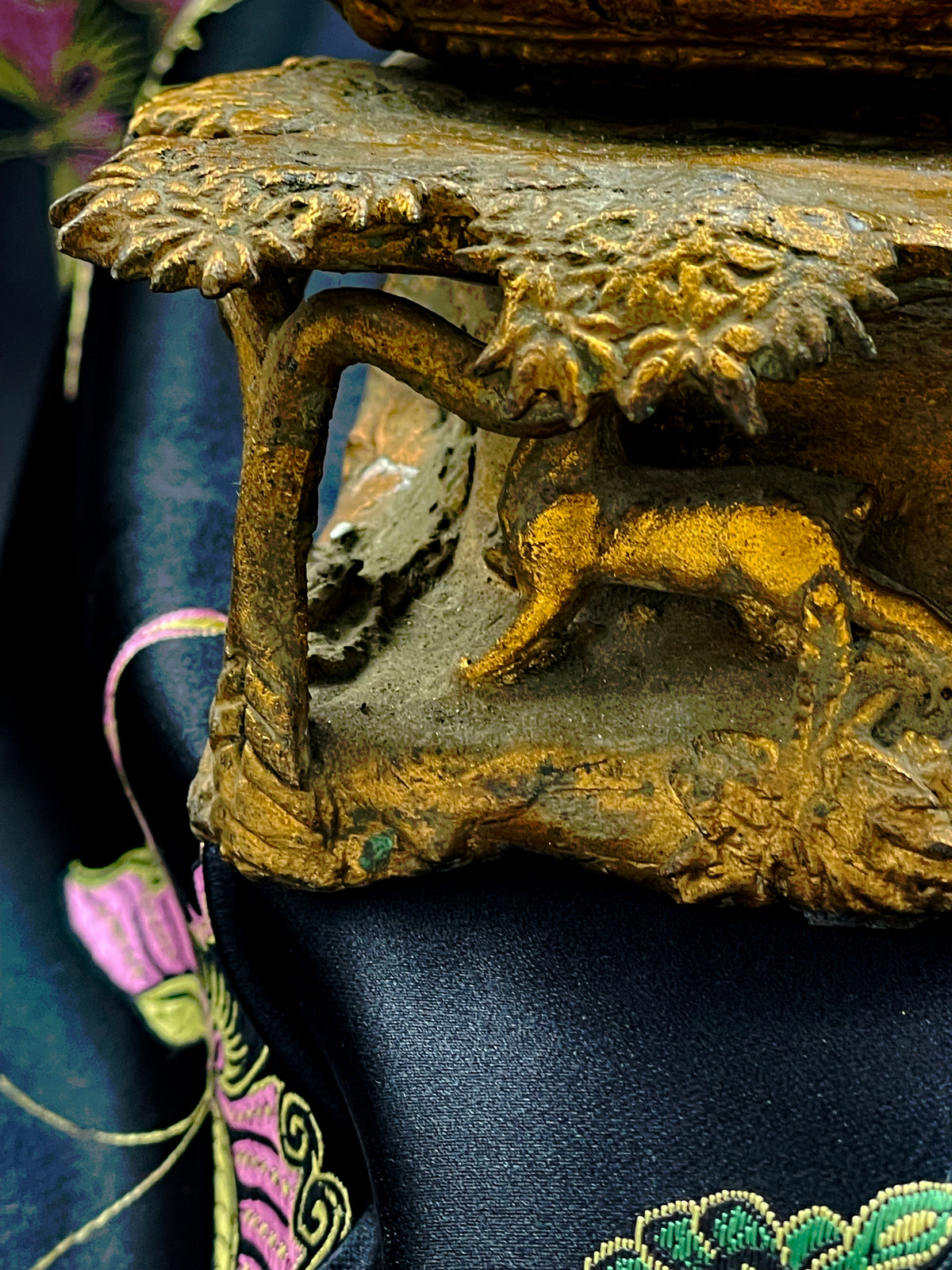 Detail of the sculpted bronze base with gilded deer grazing beneath flowering trees