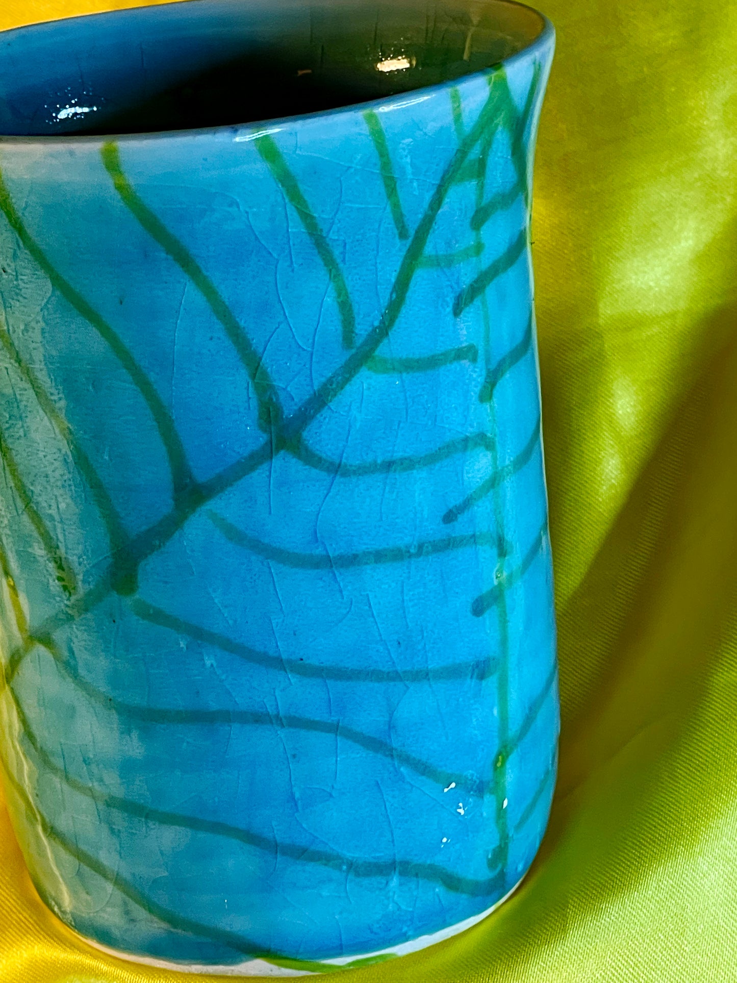 Back of the mug showing turquoise celadon glaze with hand-painted green vine decoration