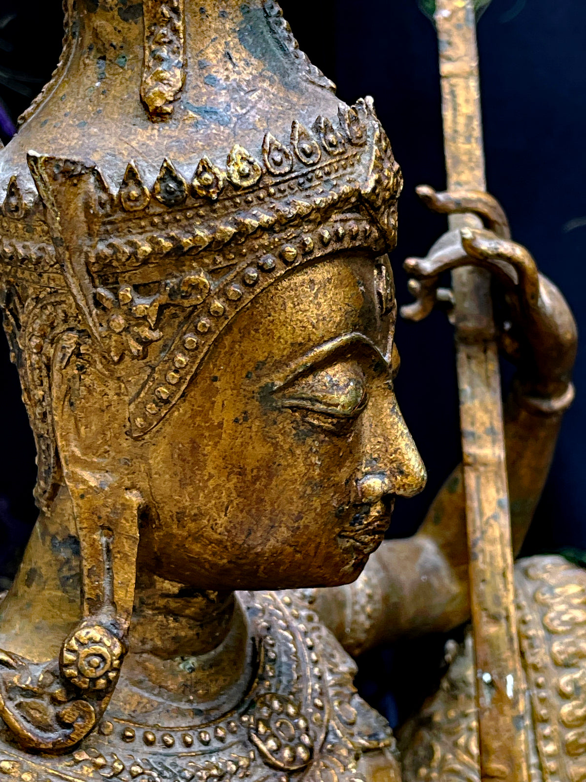 Close up profile of the crowned face of the antique Thai gilded bronze Saraswati statue