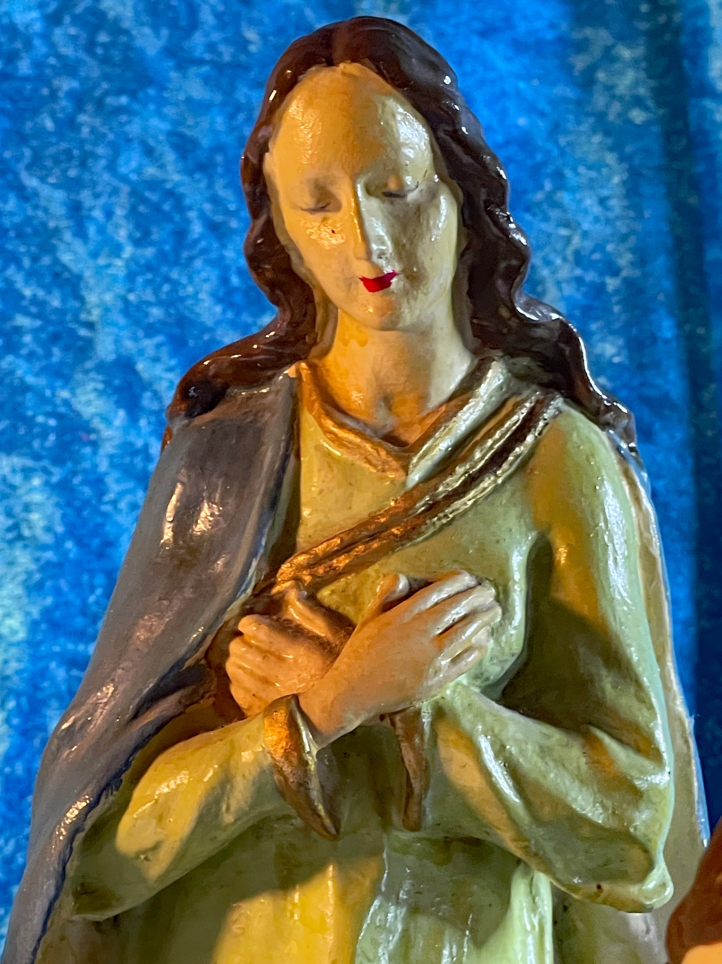 Close detail of the sage-green robed saint figure with gilded trim