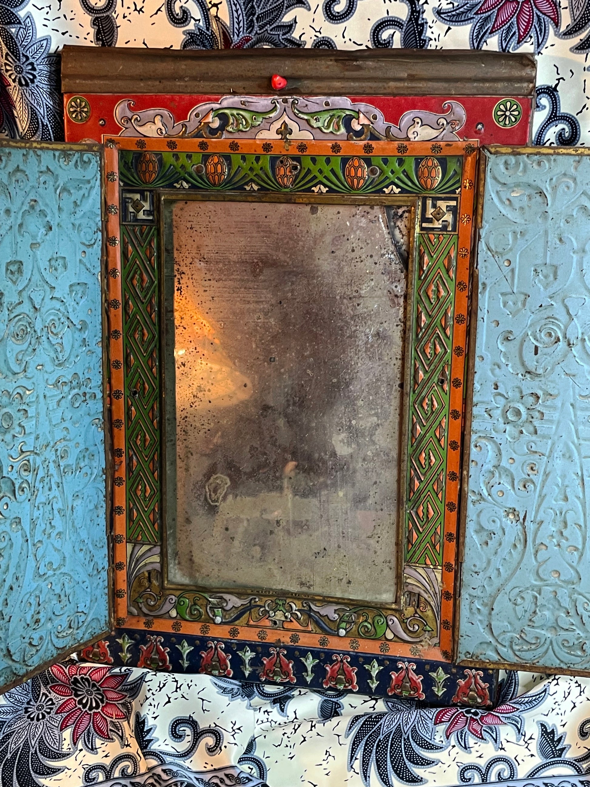 Folding mirror open and viewed straight on, mirror glass framed by green and orange painted borders