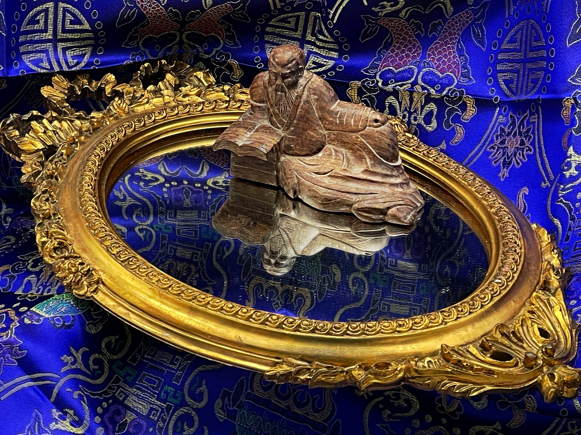 Carved Confucius figure with the full gilt oval mirror and its reflection