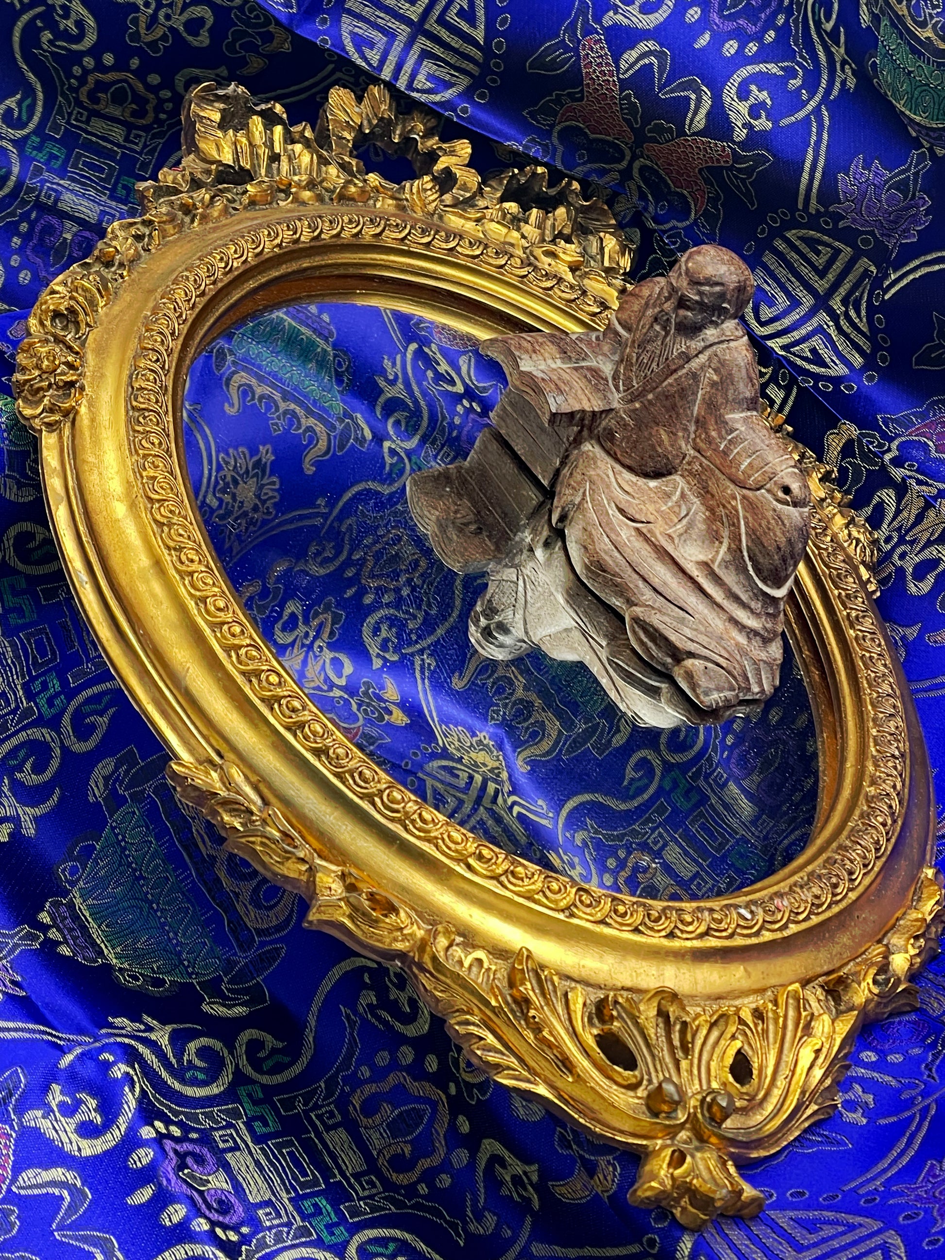 Richly ornamented gilt oval mirror with carved scrollwork frame