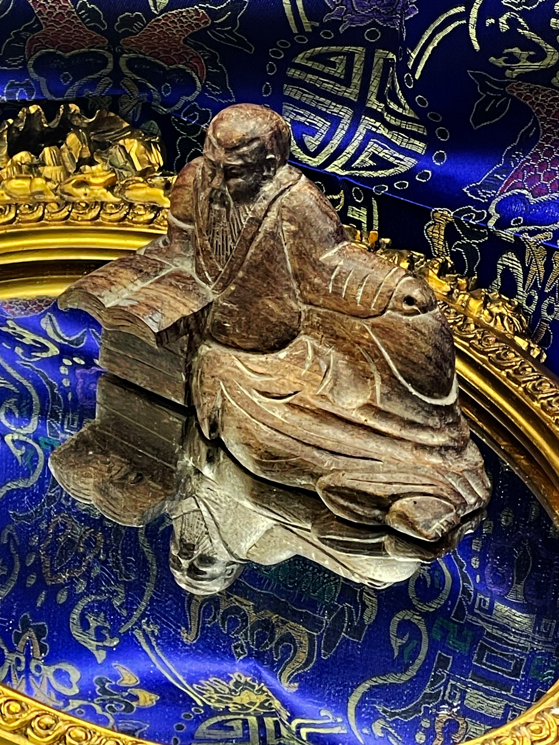Confucius sculpture mirrored in the gilt-framed glass