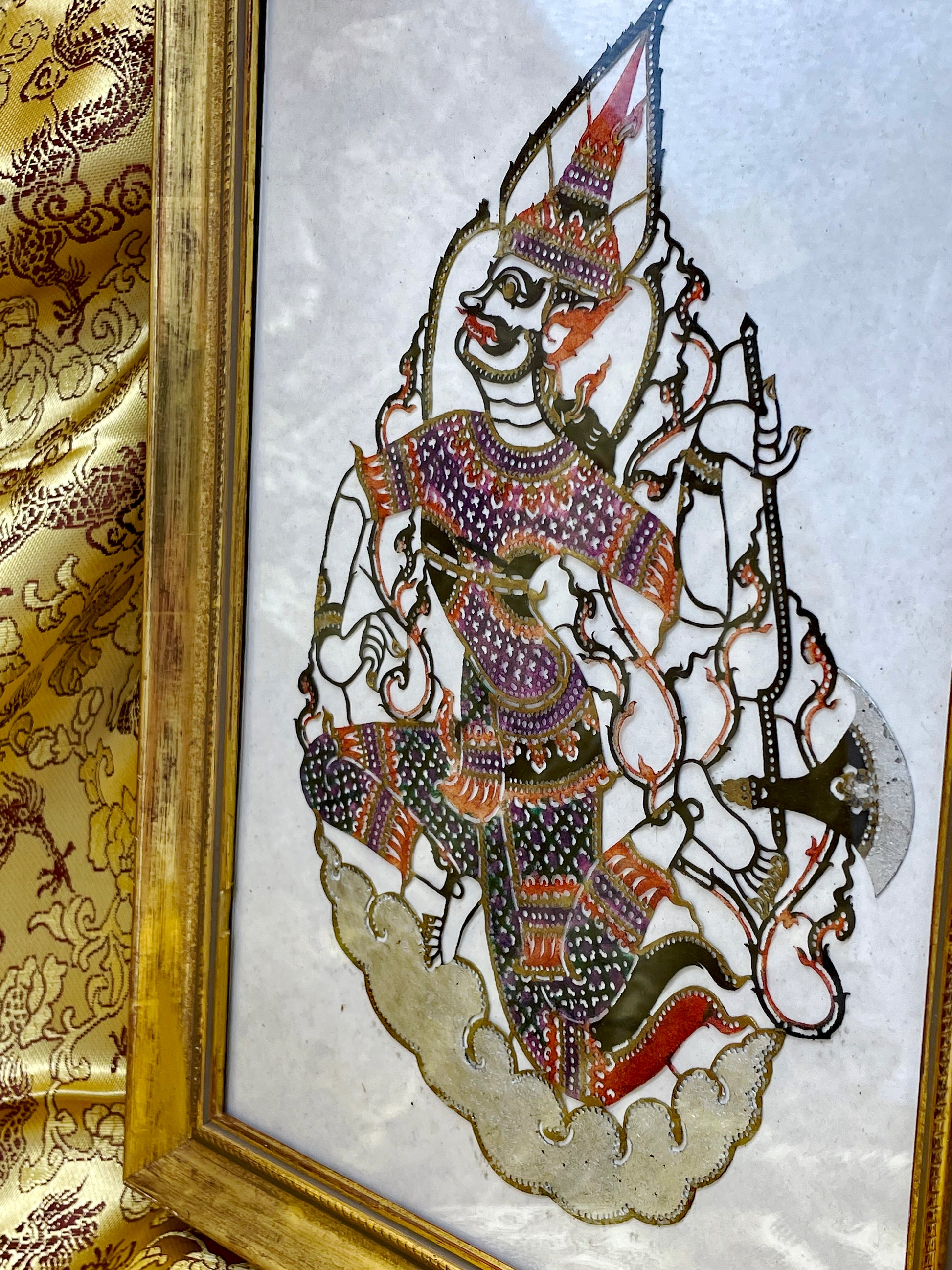 Gilt-framed Indonesian wayang leather deity panel viewed at an angle