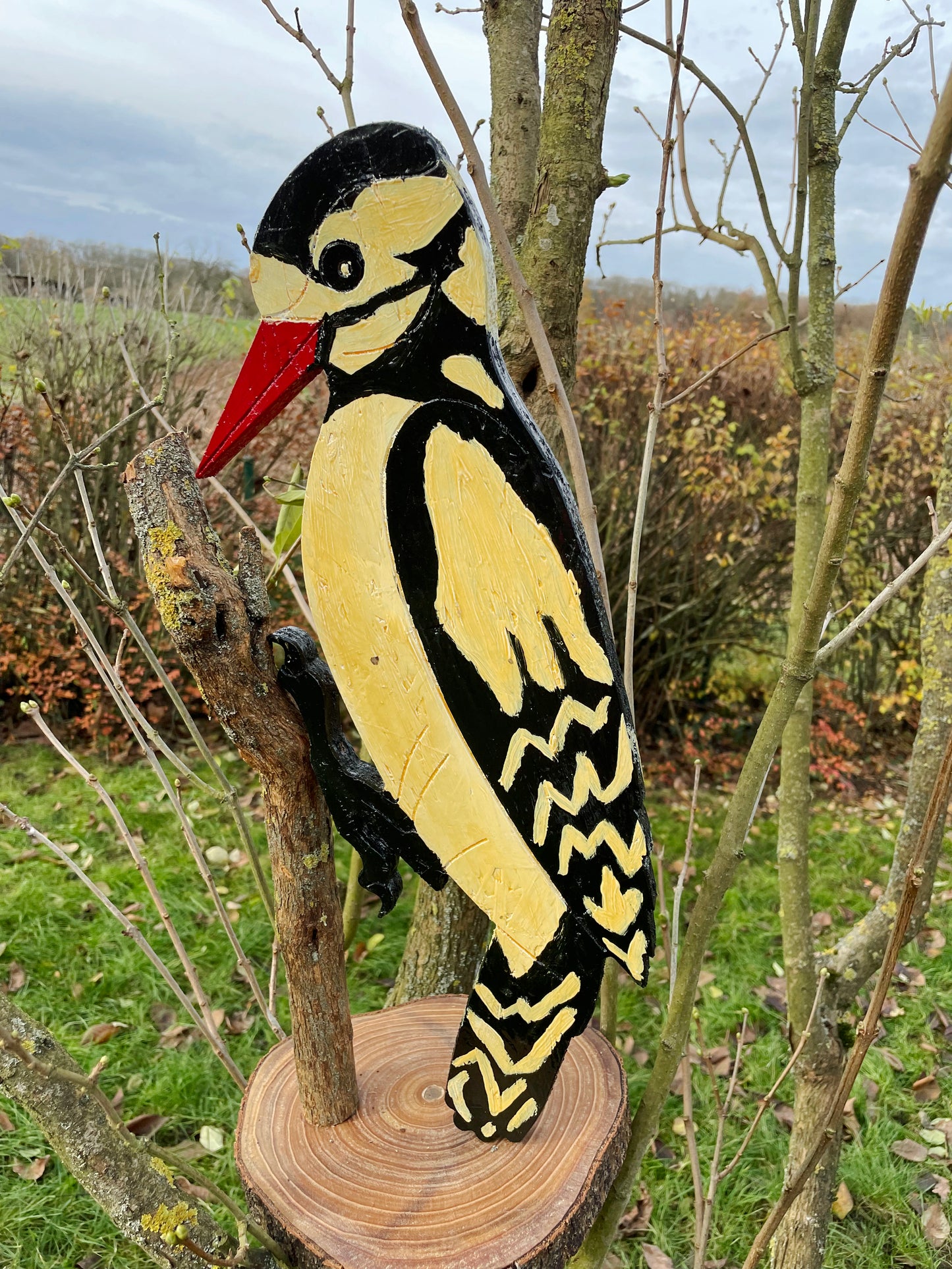 Vintage wooden woodpecker garden sculpture, black yellow and red painted plumage, side view