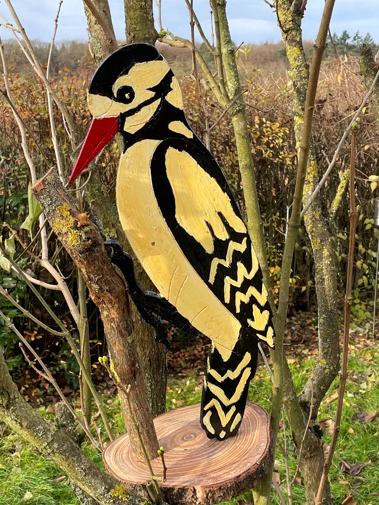 Hand-carved hand-painted wooden woodpecker folk-art sculpture on log base, full profile