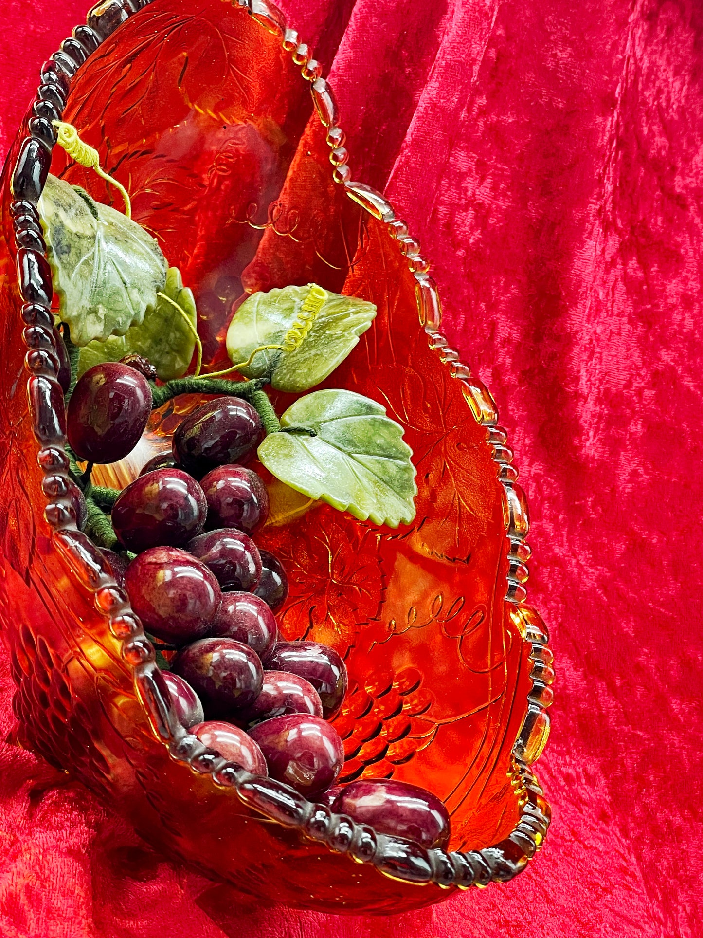 Angled view of the amber glass bowl with hardstone grape cluster and jade vine leaves