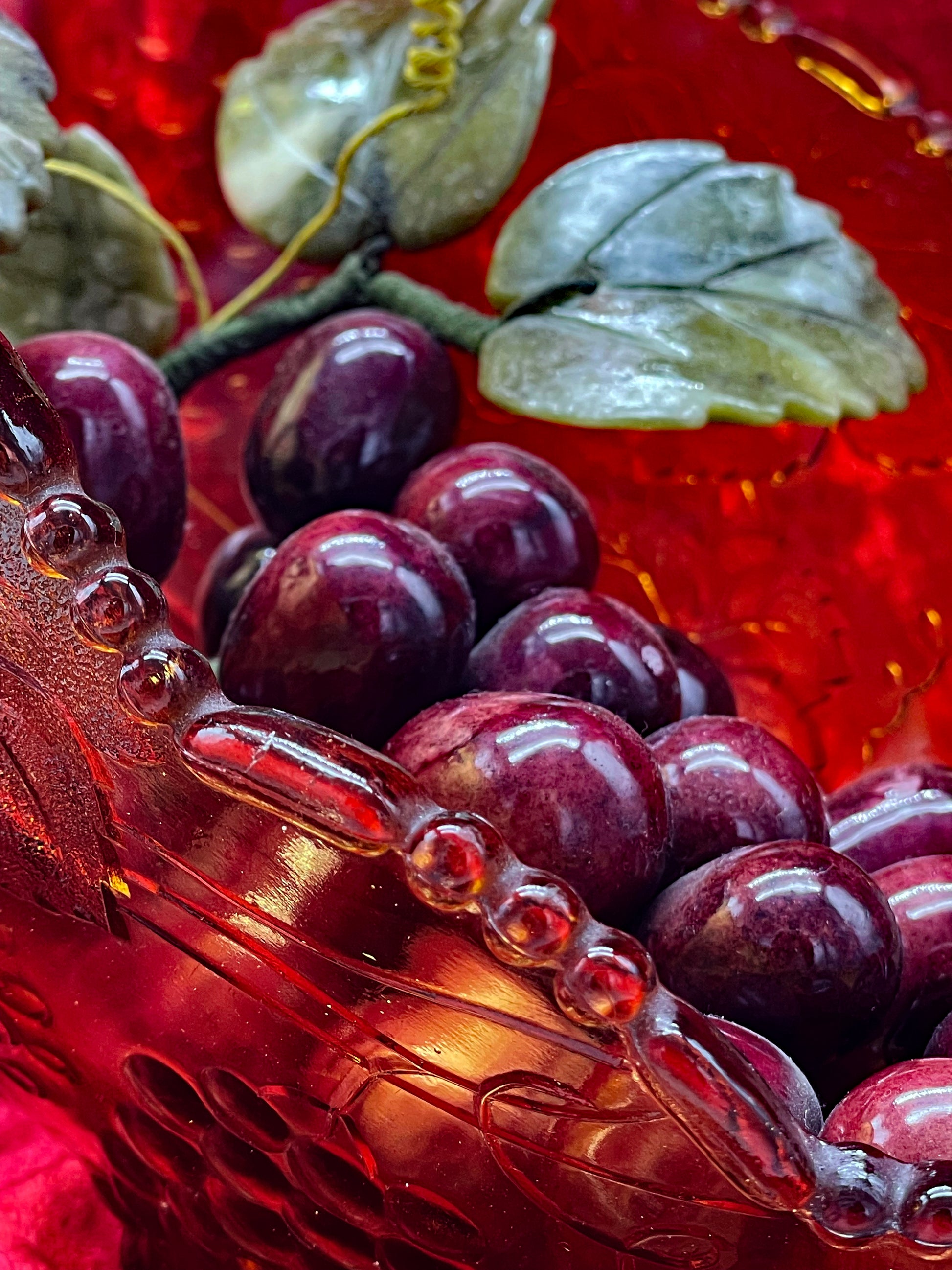 Close-up of carved amethyst grapes and a veined jade leaf