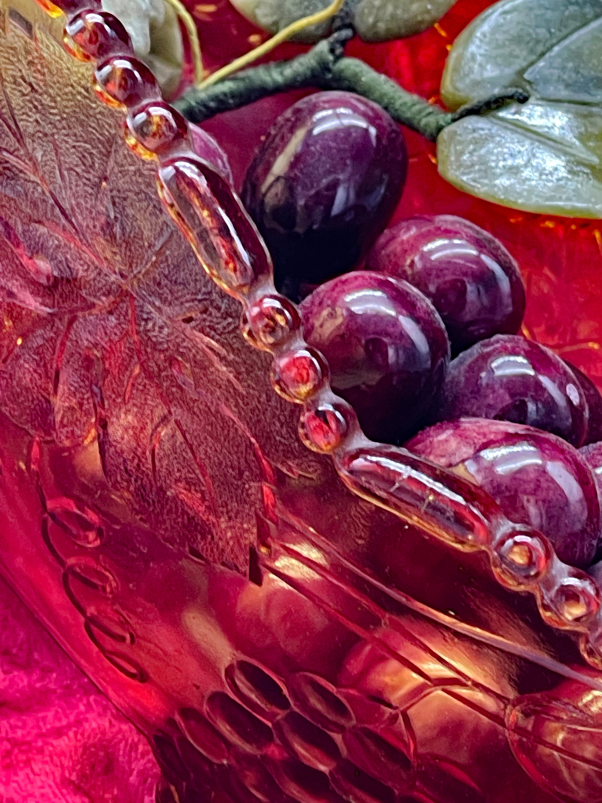 Close-up of the chunky beaded rim and amethyst grapes inside the amber bowl