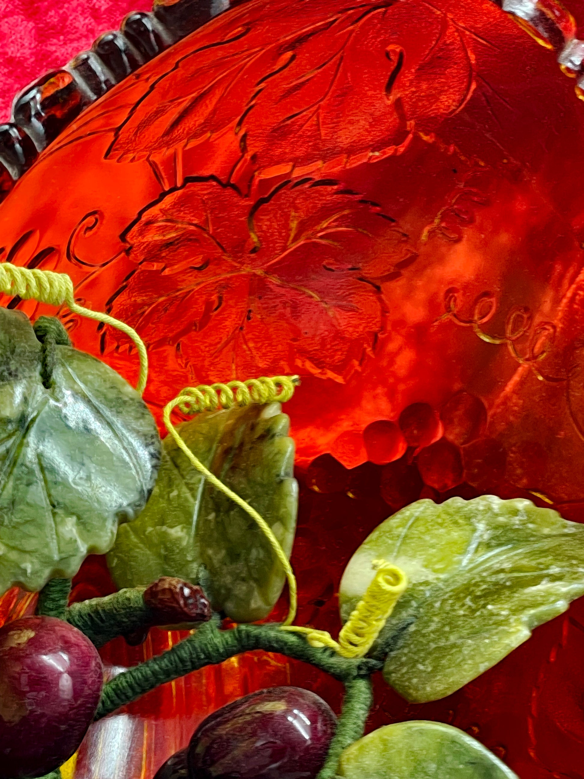 Macro of the amber glass grape and vine-leaf relief with jade tendrils