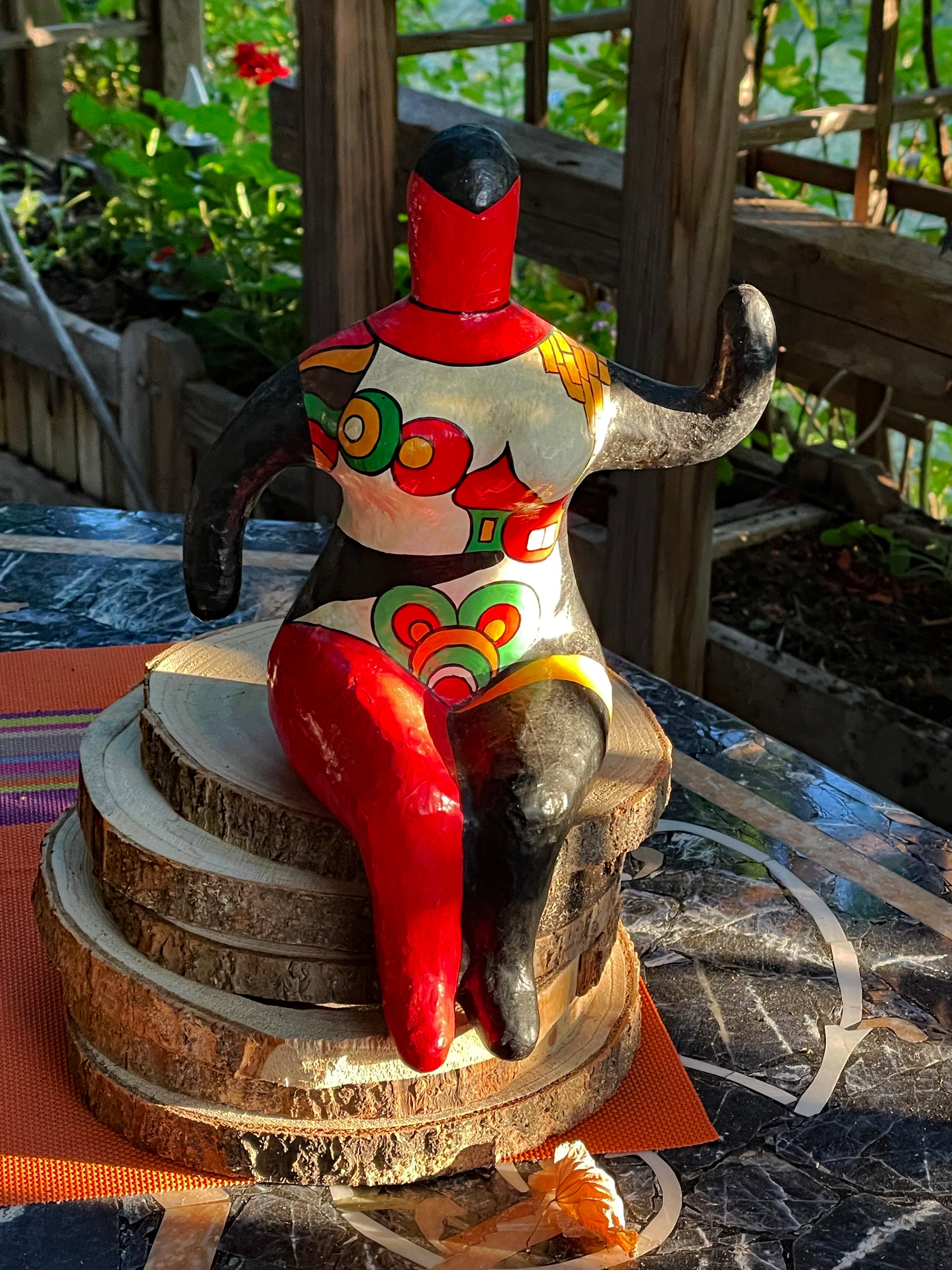 Nana figure in a garden setting, colourful hand-painted sculpture