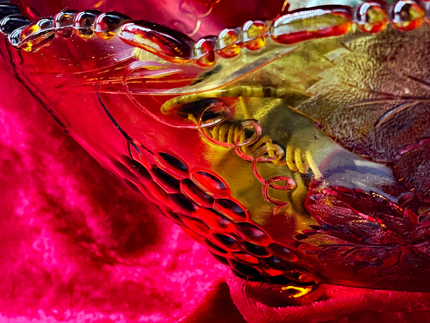 Detail of the moulded grape cluster relief and beaded rim on the amber glass