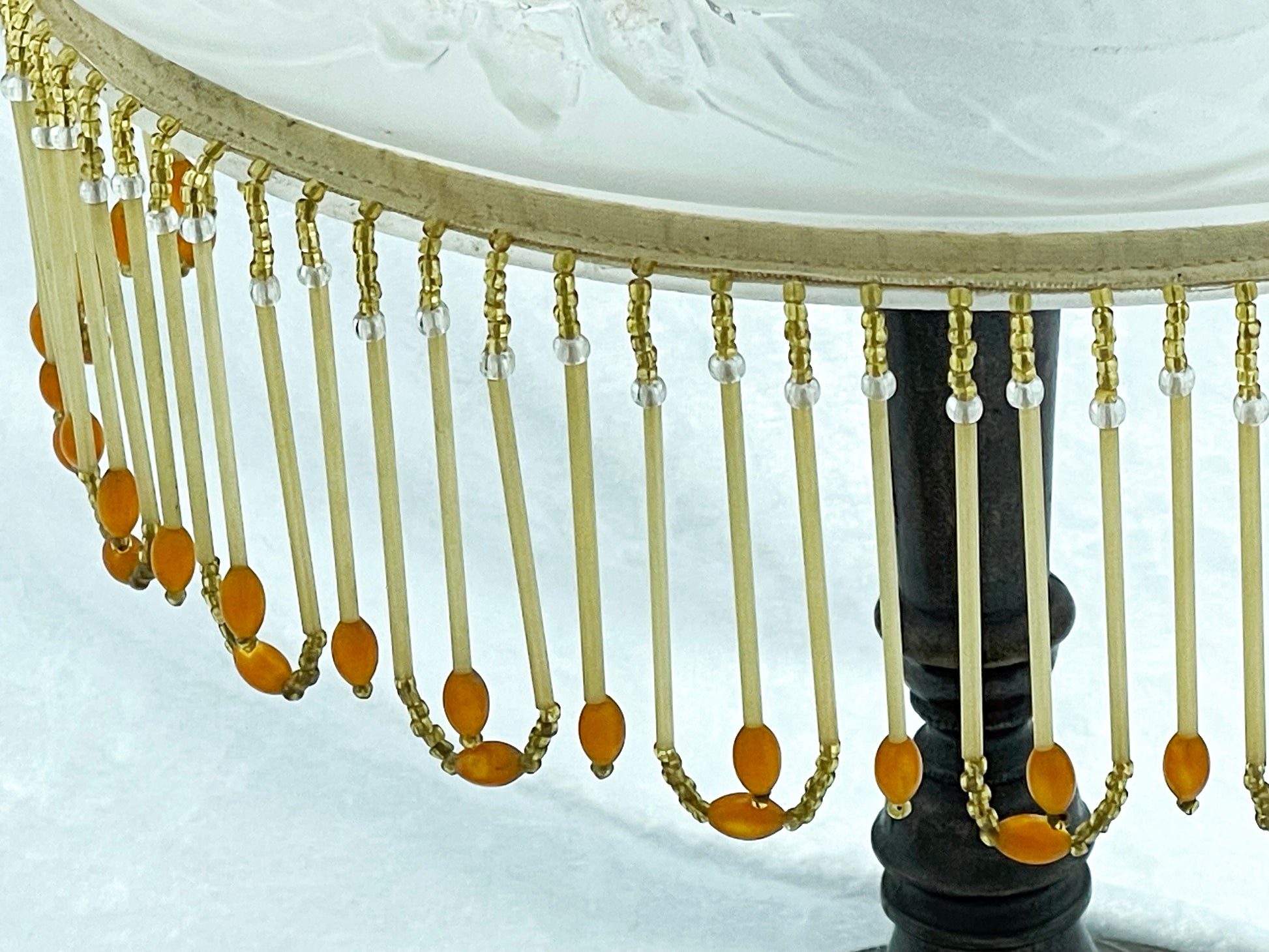 Angled detail of amber and clear glass beaded fringe hanging from the shade rim
