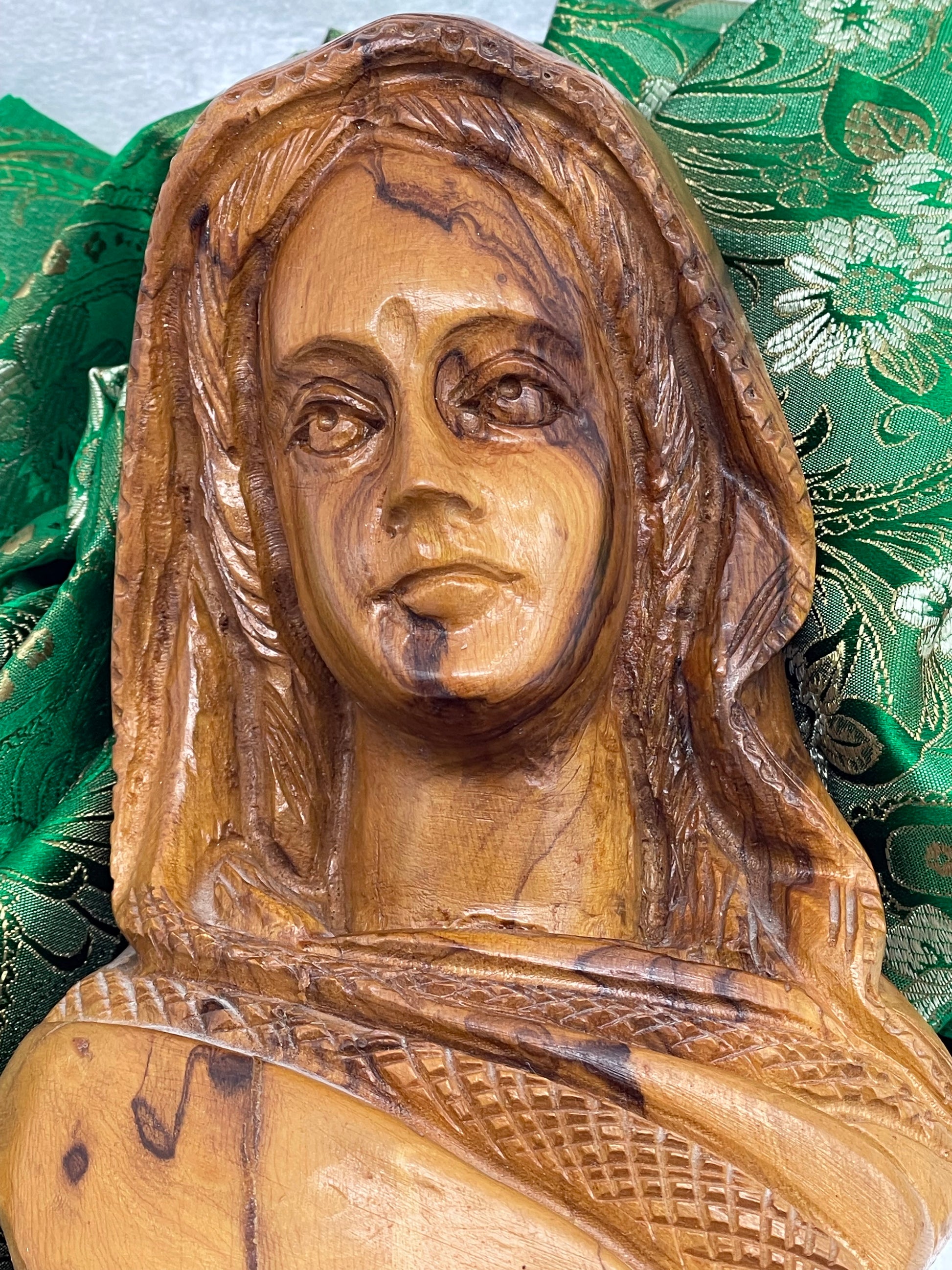 Close-up of carved shawl lattice and plaited hair detail in olive wood
