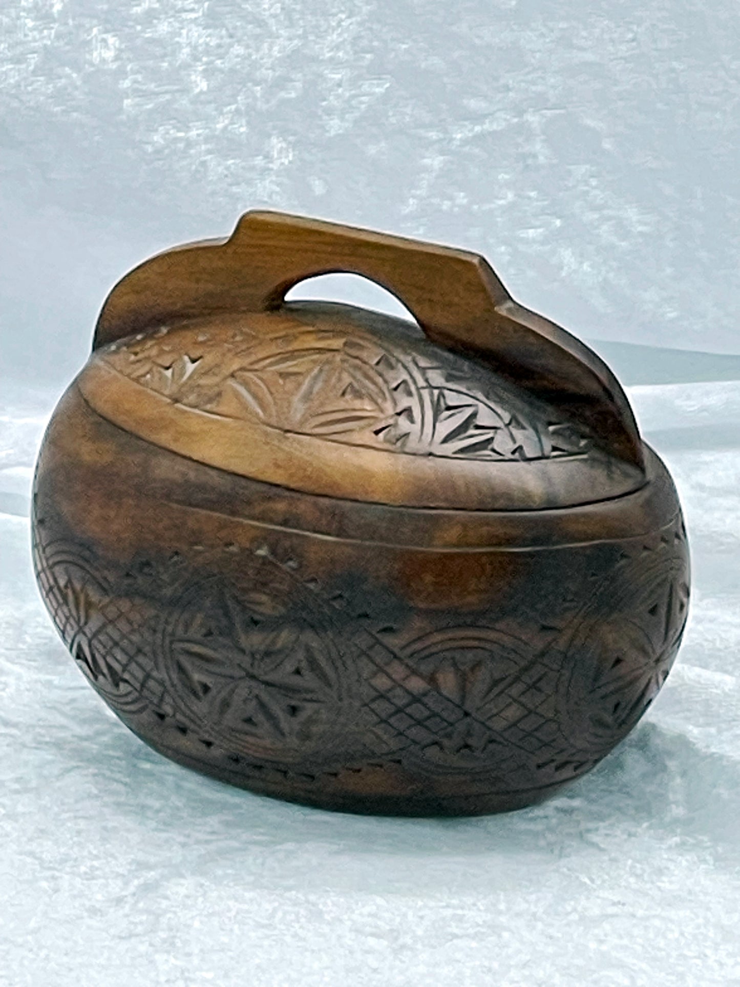 Carved wooden trinket box closed, showing geometric rosette carving across lid and body