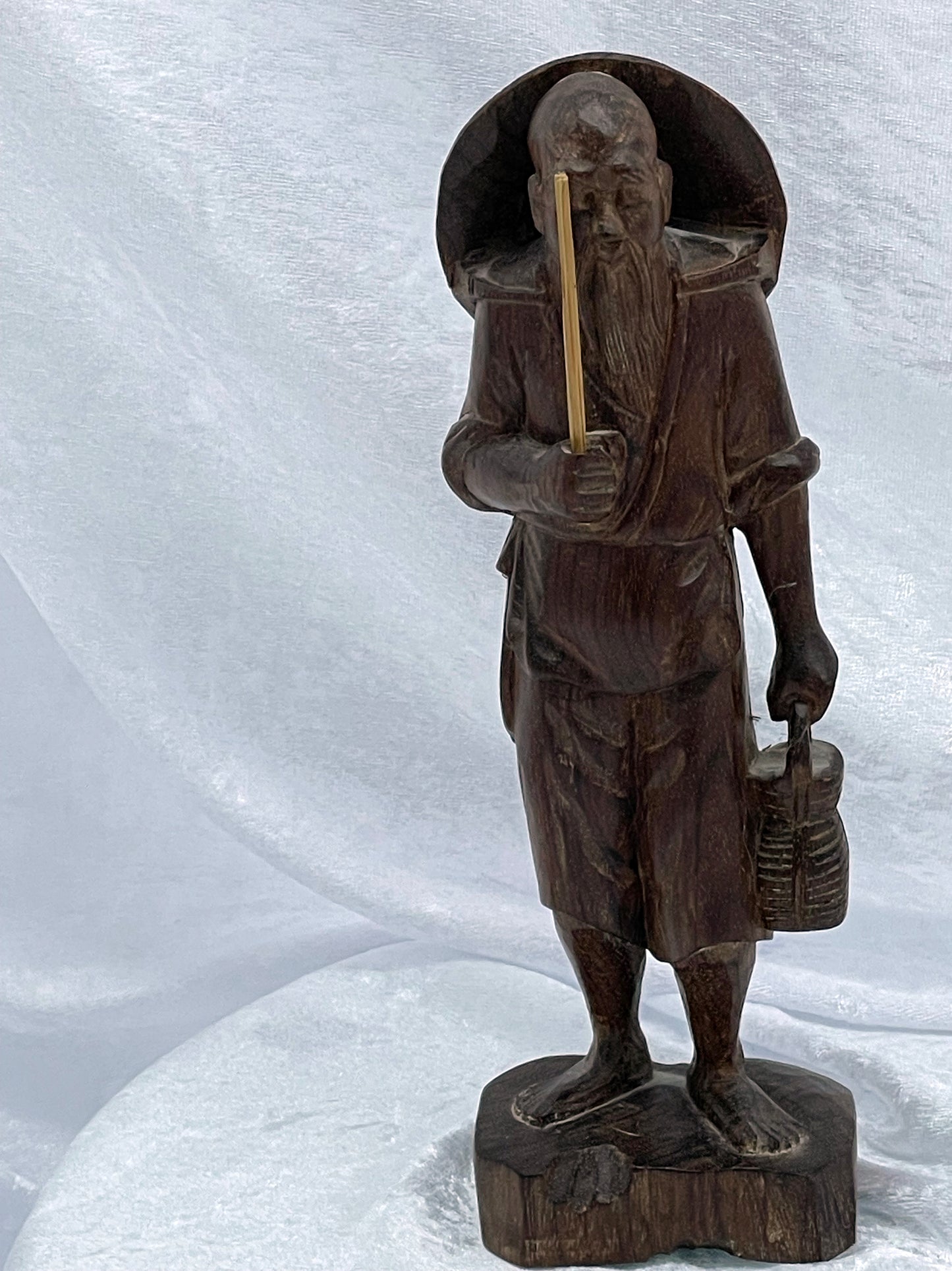 Carved hardwood sage fisherman figure with staff and lantern, three-quarter view