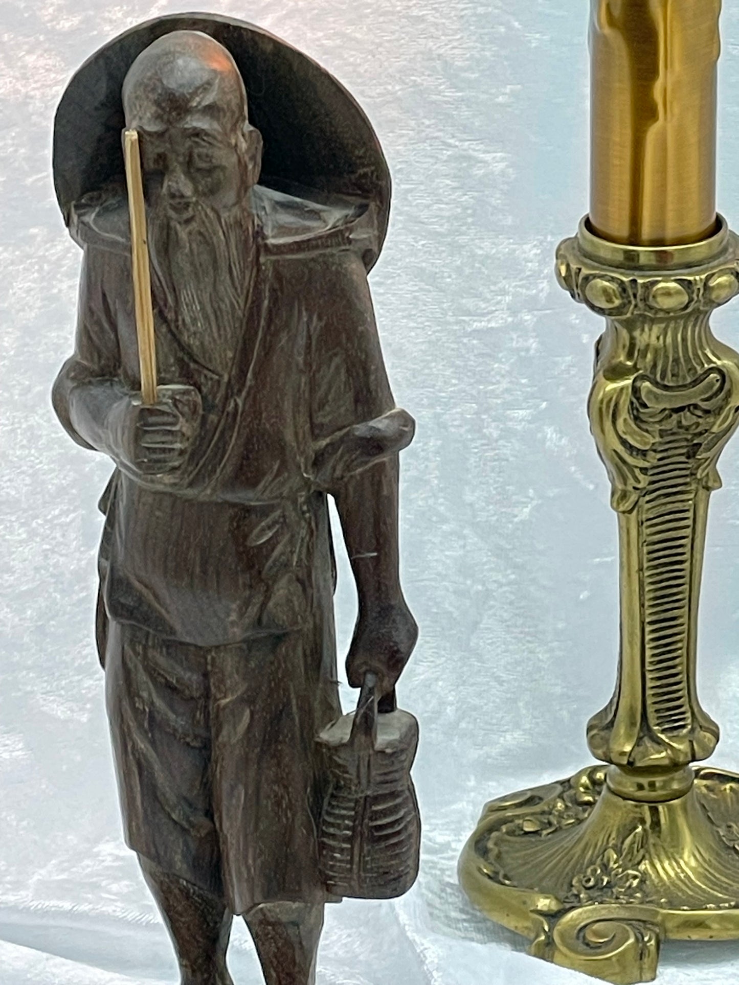 Three-quarter detail of the carved robes, hat and staff of the sage figure