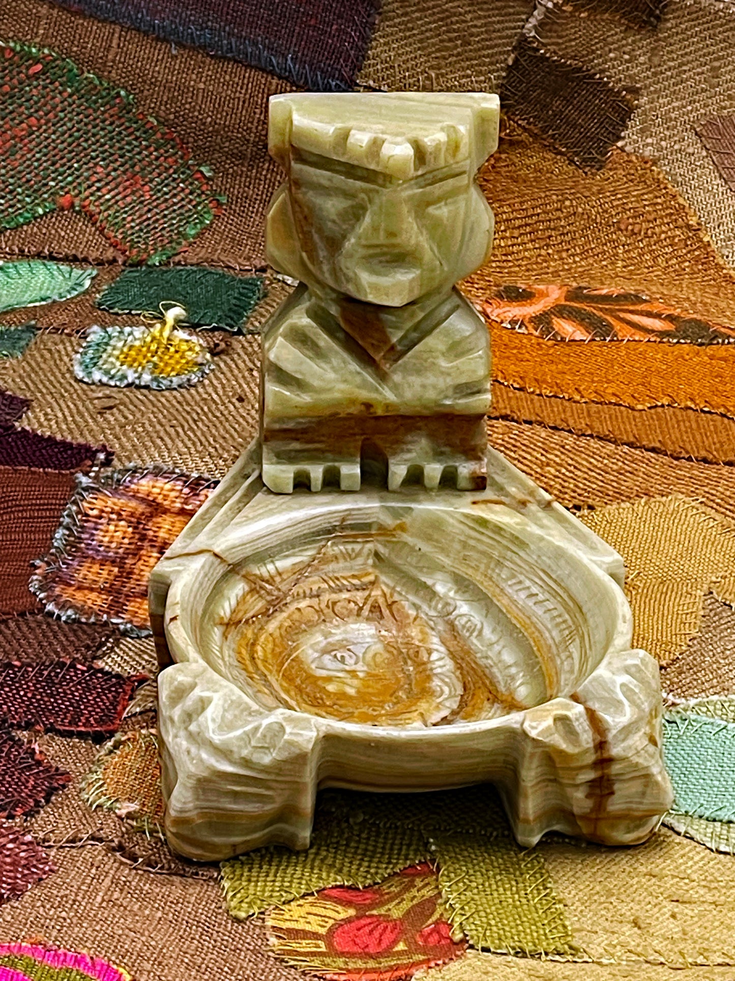 Close detail of carved Aztec deity face and stepped headdress in onyx marble