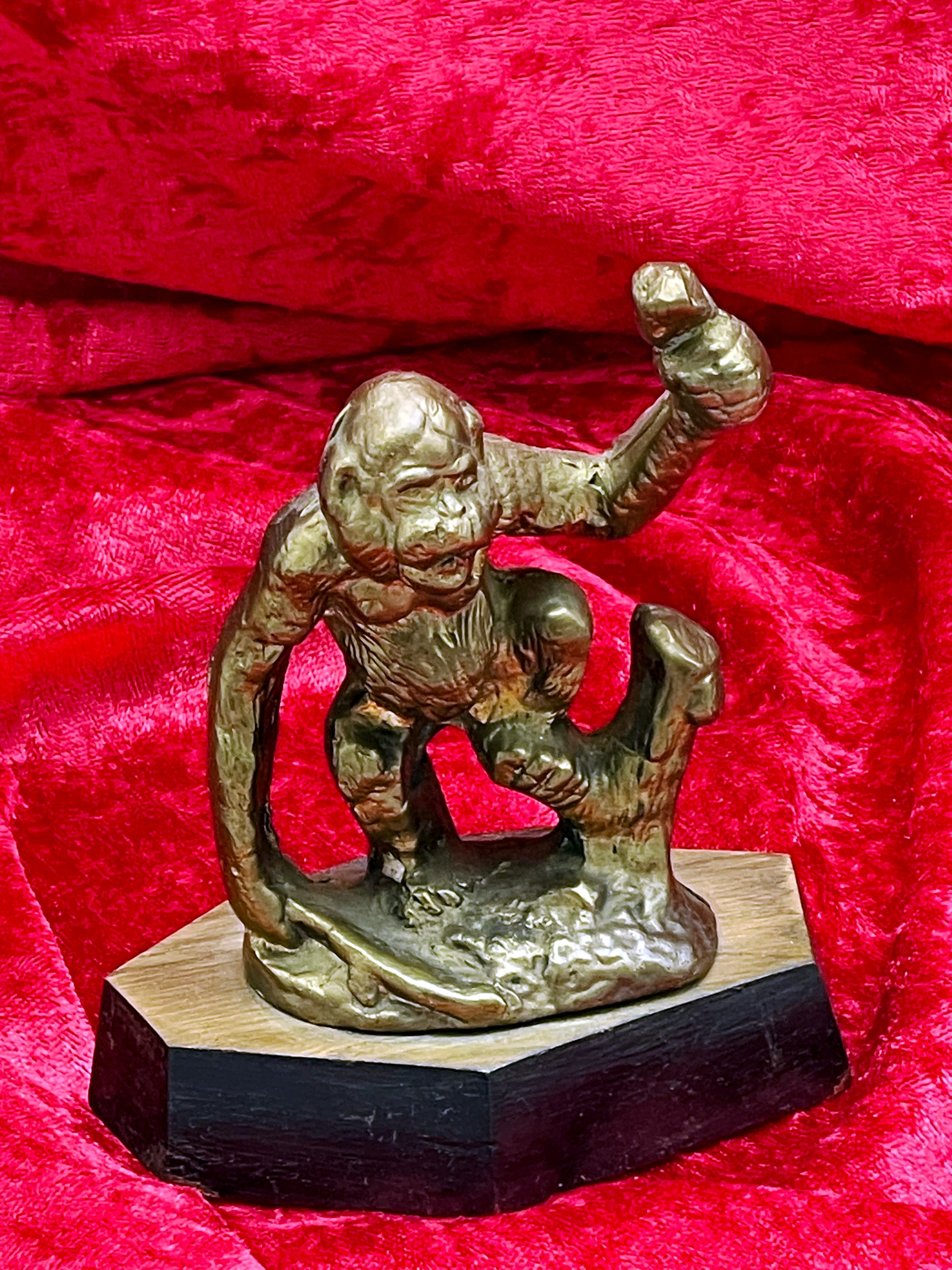 Vintage bronze ape figure on wooden base, full 3/4 view of crouching gorilla with raised fist