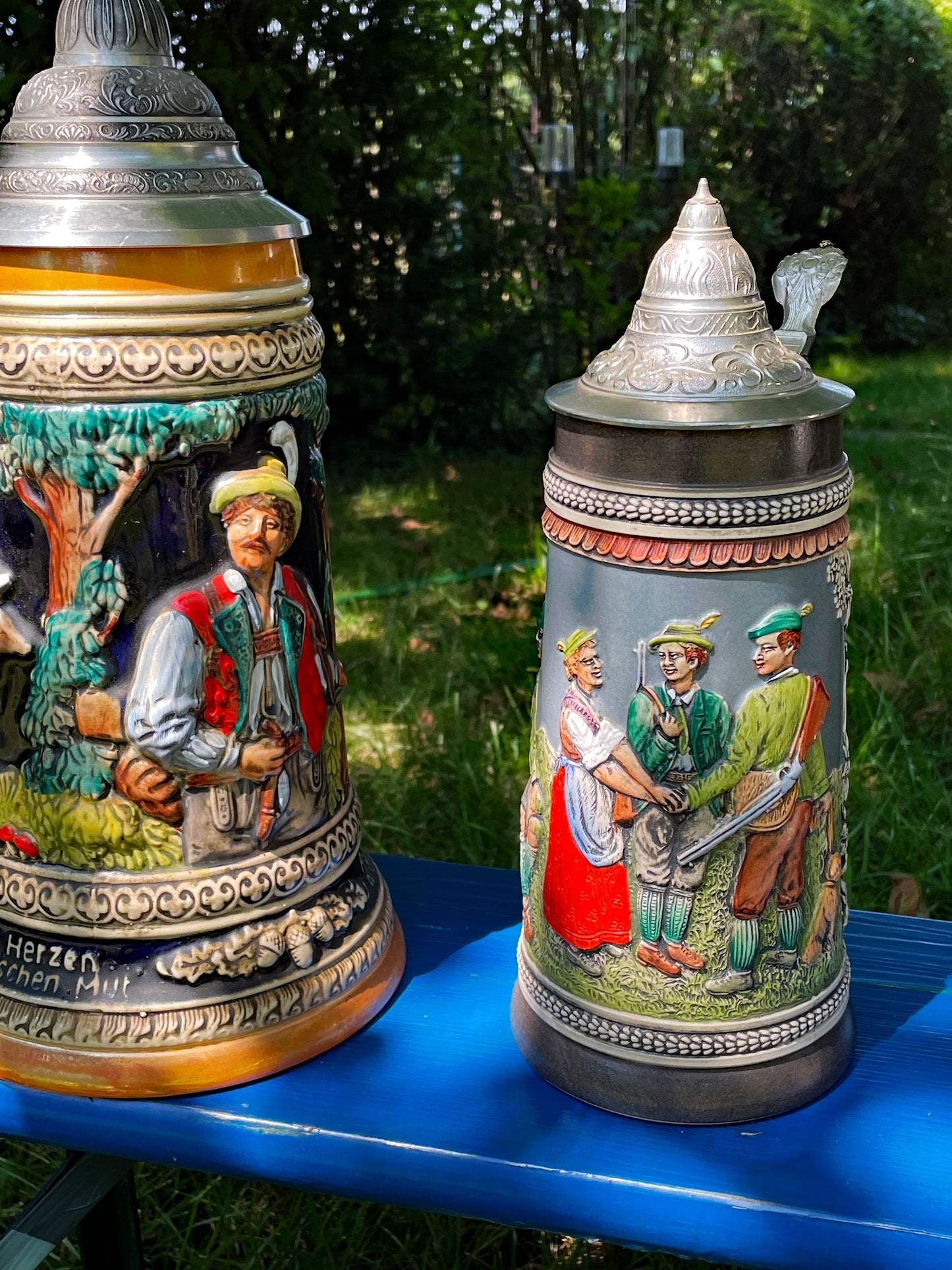 Four hand-painted German Bierkrüge in a row, cobalt and polychrome relief scenes