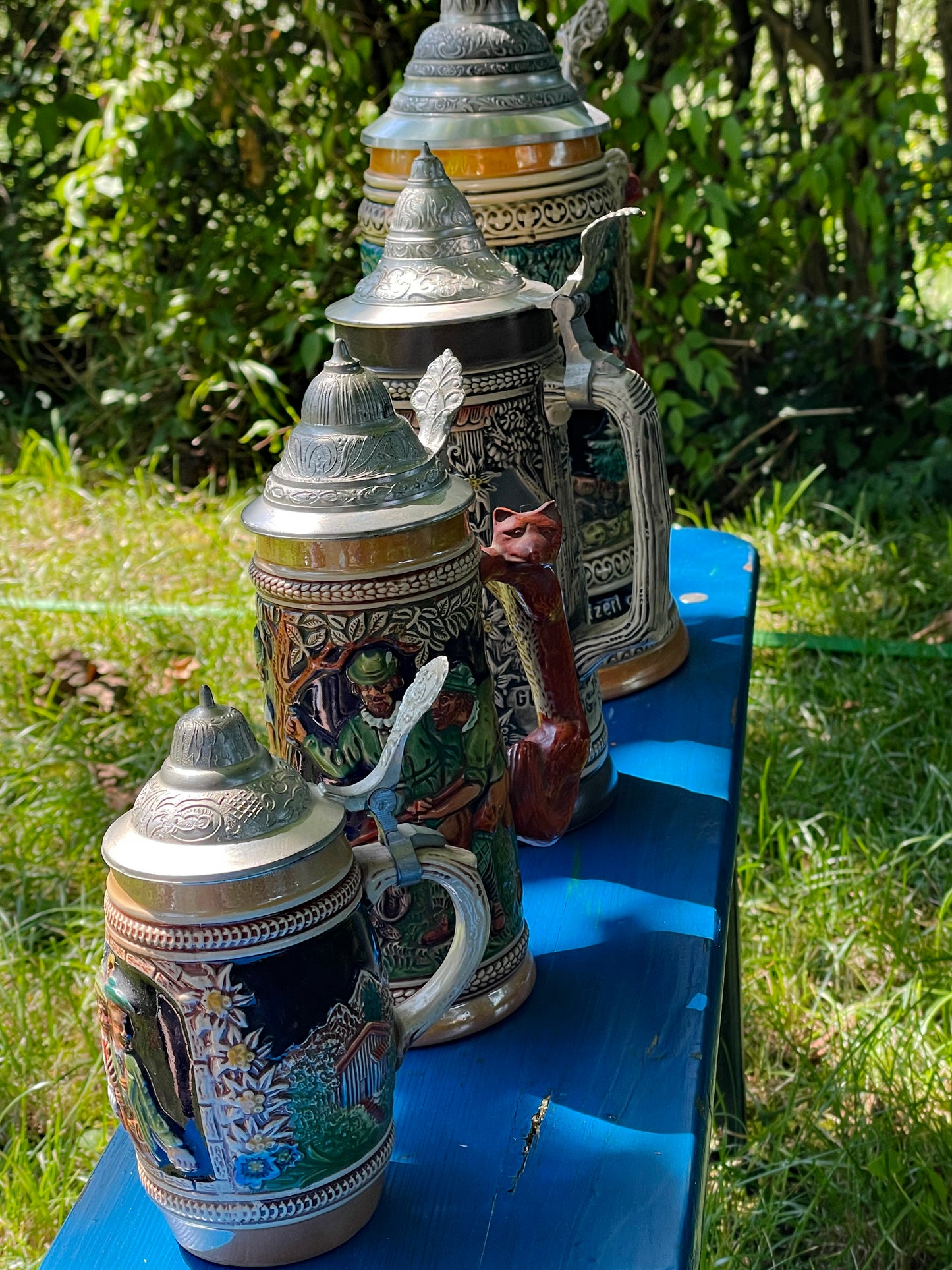 Set of four colourful German relief beer steins with pewter lids, graduated sizes